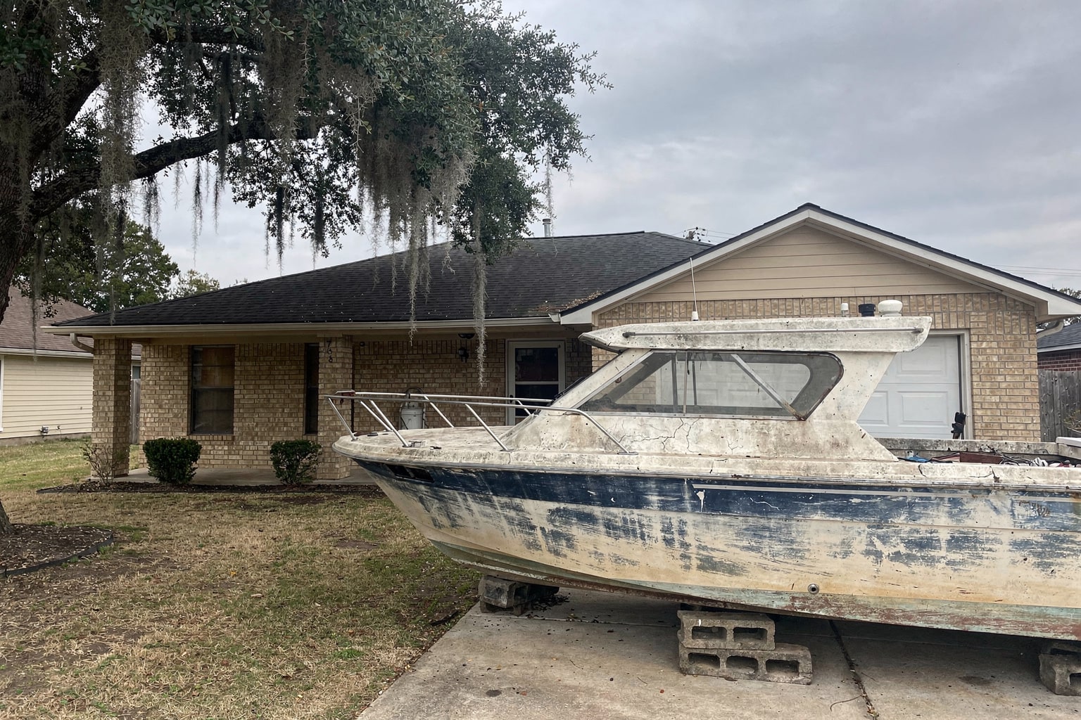 Junk boat disposal in Arlington Texas, weathered cabin cruiser staged on blocks for removal service