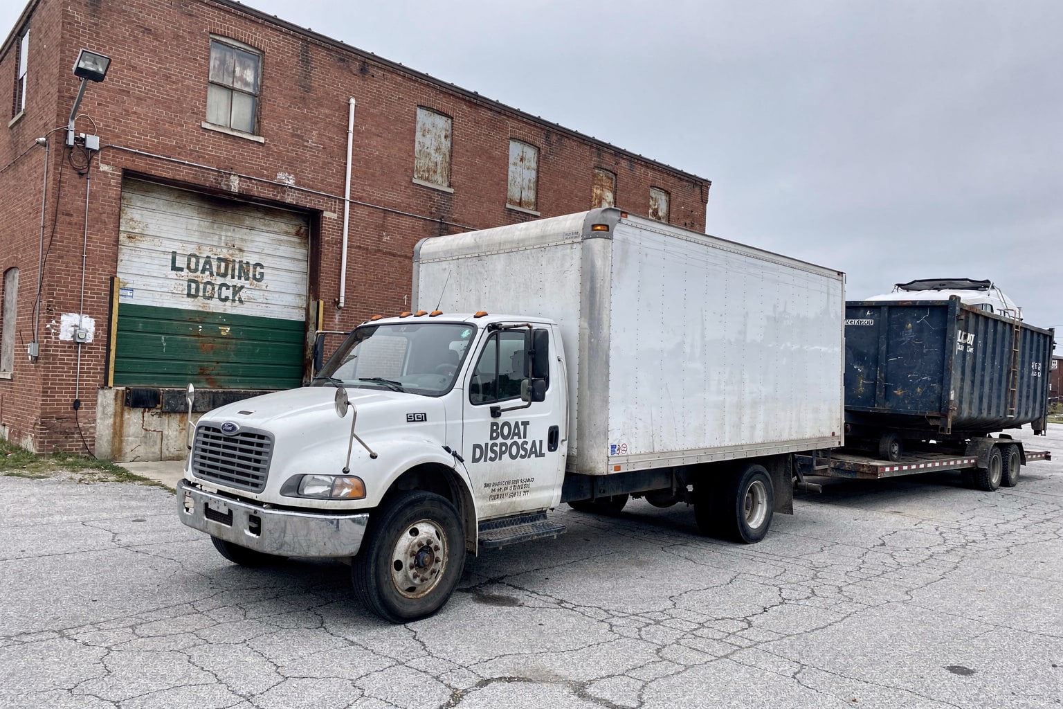 Boat disposal Tulsa Oklahoma - commercial truck and flatbed trailer loaded with multiple boats at warehouse lot