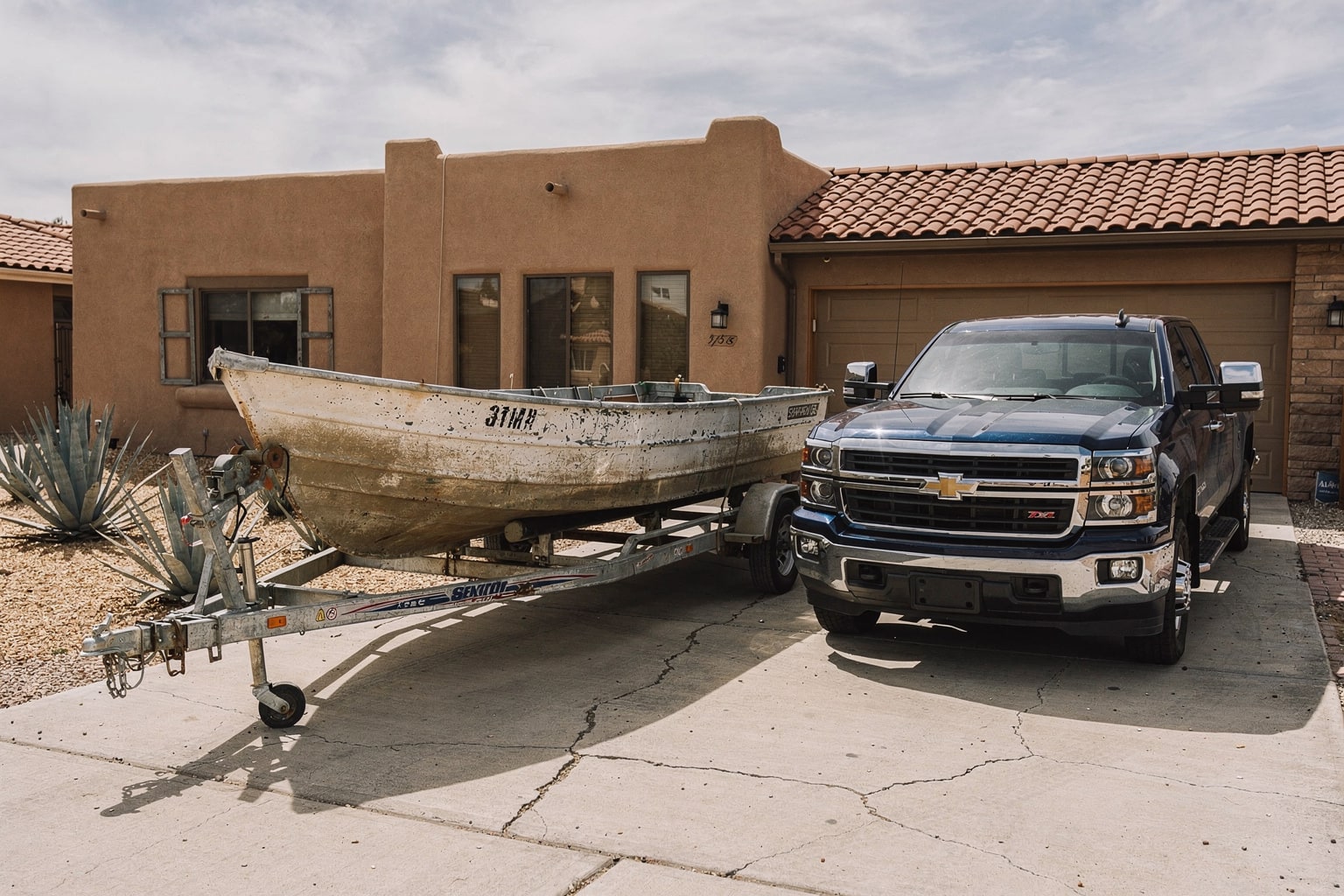 Junk boat removal in Albuquerque with aluminum fishing boat on trailer attached to pickup truck in residential driveway