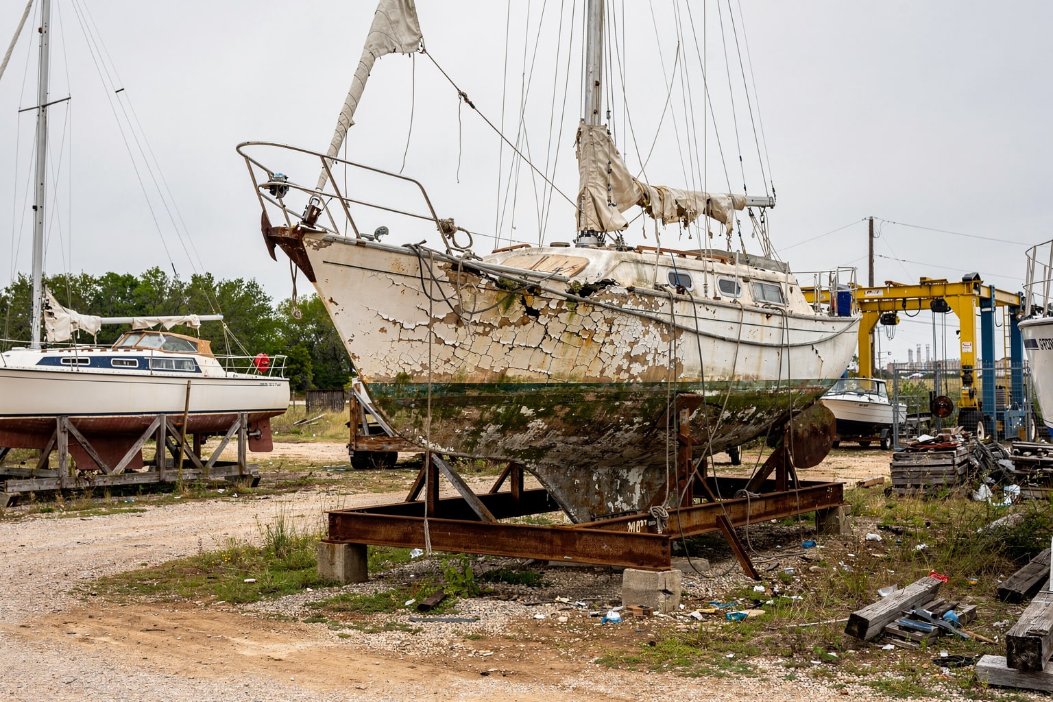 Marine salvage Arkansas boatyard: damaged sailboat on cradle in commercial junk boat storage facility