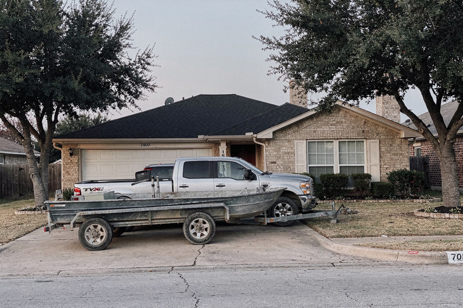Junk boat removal in Arlington TX with weathered aluminum fishing boat loaded on trailer behind pickup truck