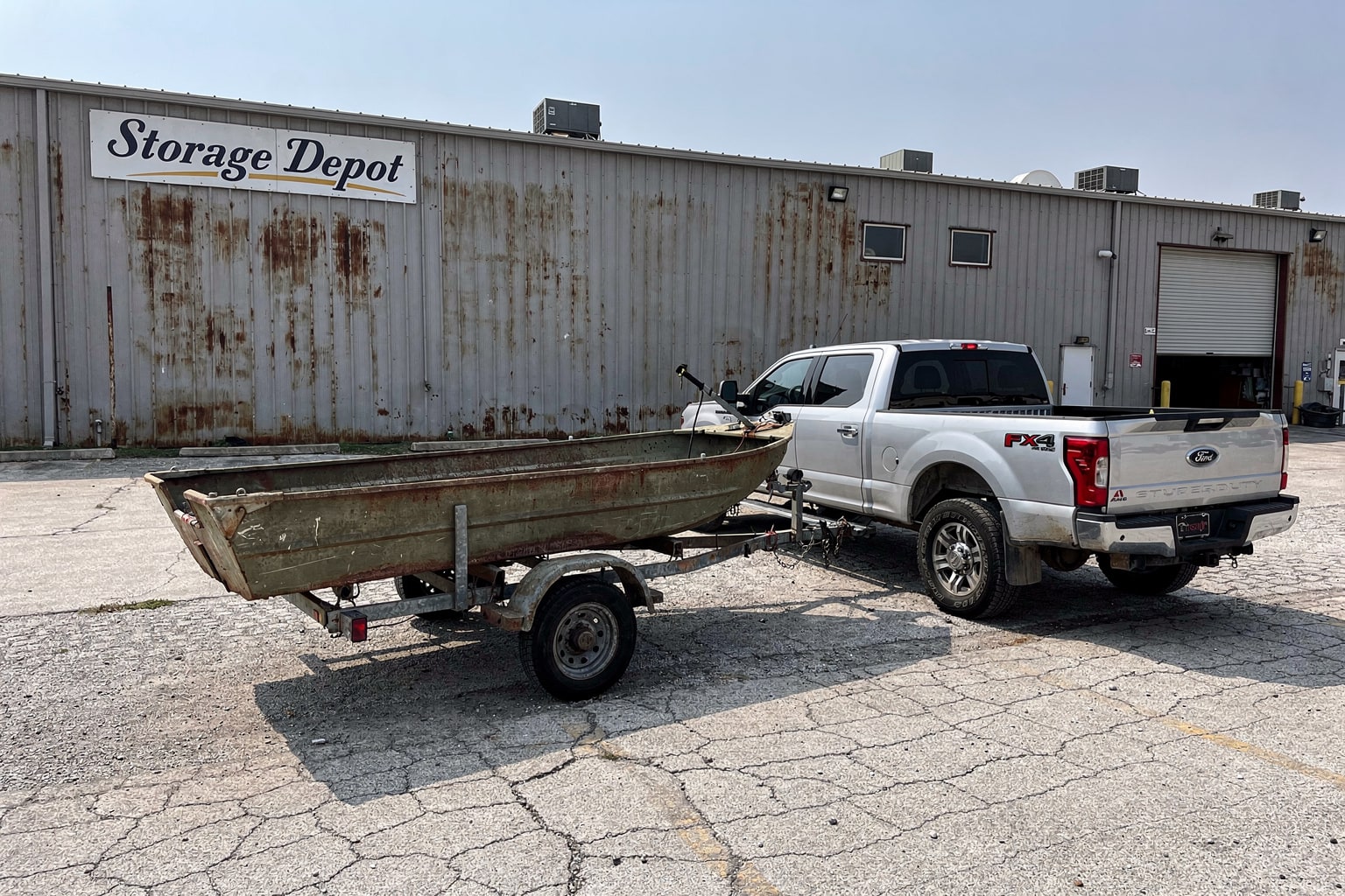 Junk boat removal service: weathered aluminum fishing boat removal at Austin commercial storage facility
