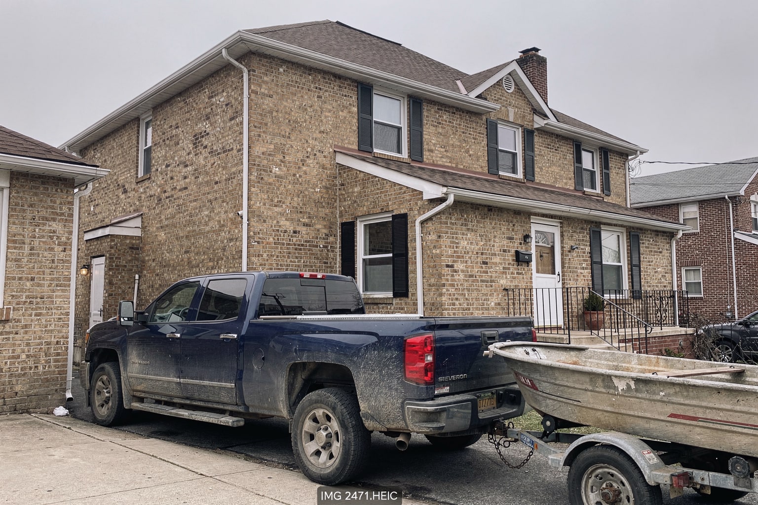 Junk boat removal Bronx driveway, aluminum fishing boat loaded on trailer behind pickup truck