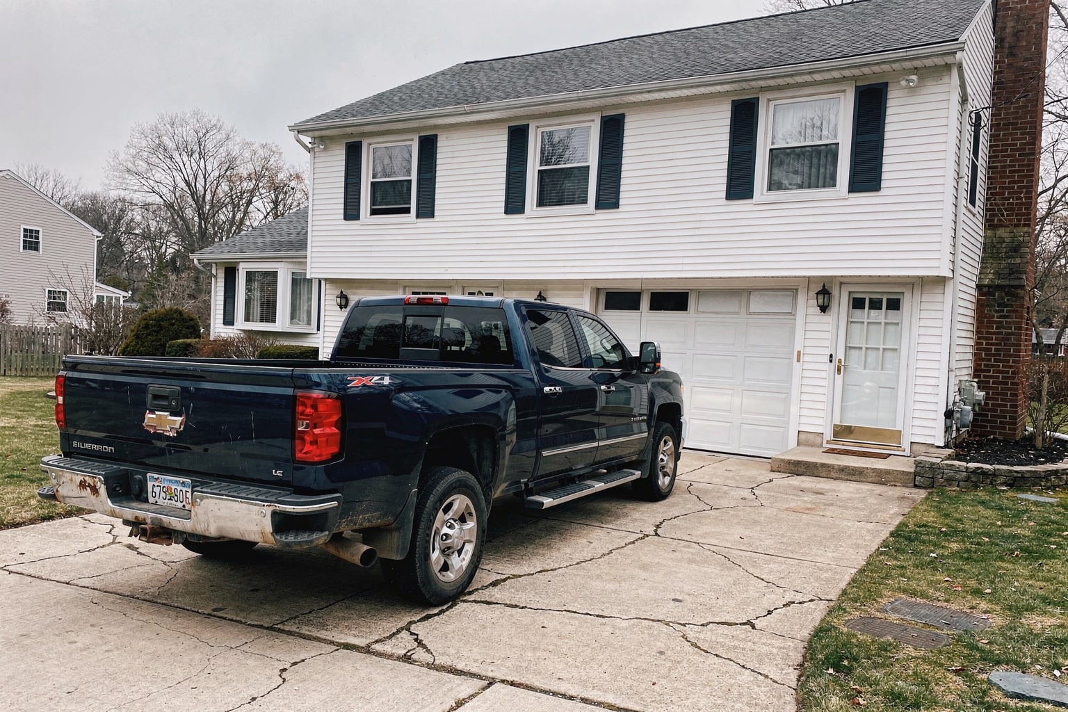 Junk boat removal Brookhaven NY — weathered 22-foot powerboat on trailer behind pickup truck in residential driveway