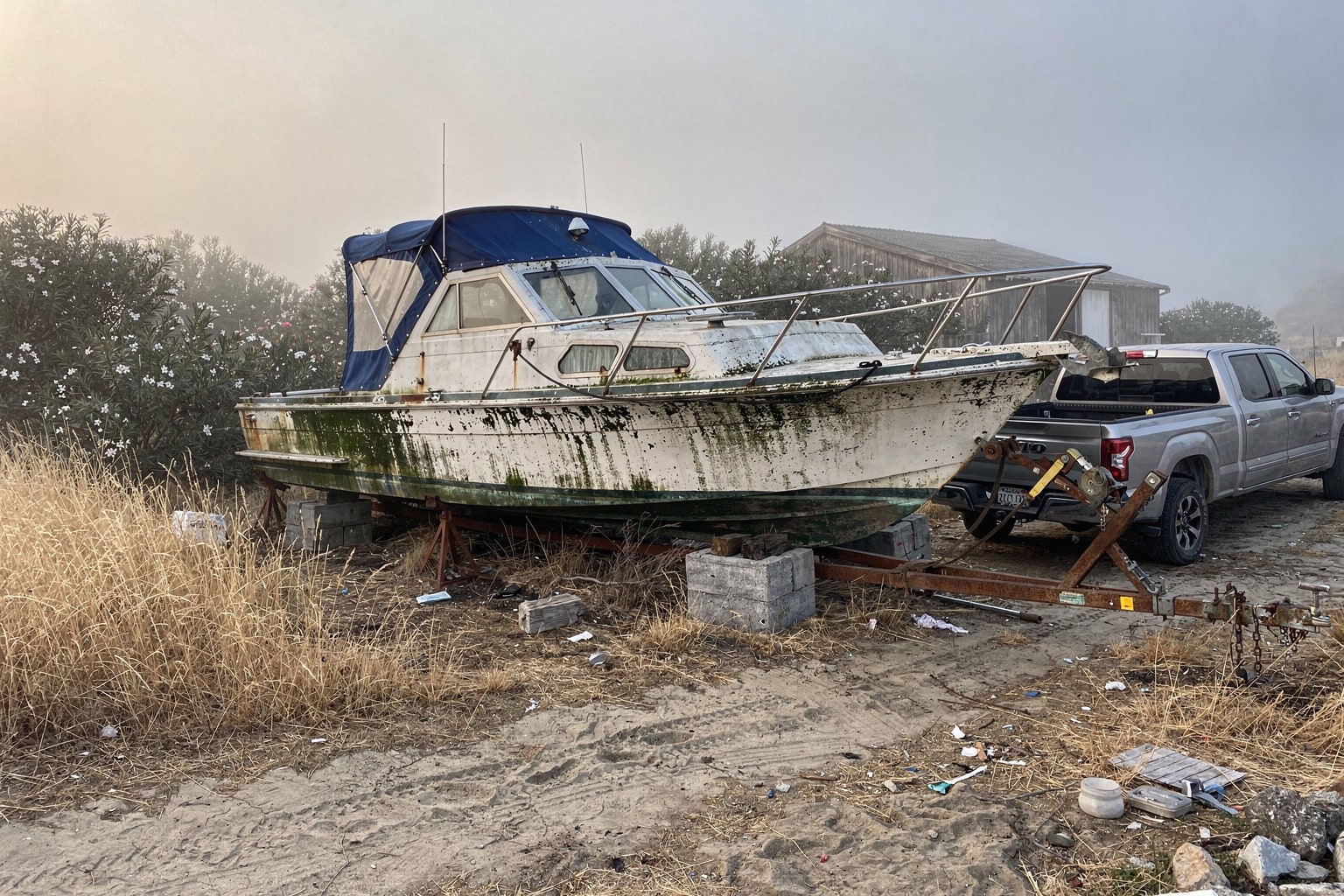 Abandoned junk boat on blocks in overgrown California lot ready for marine salvage removal