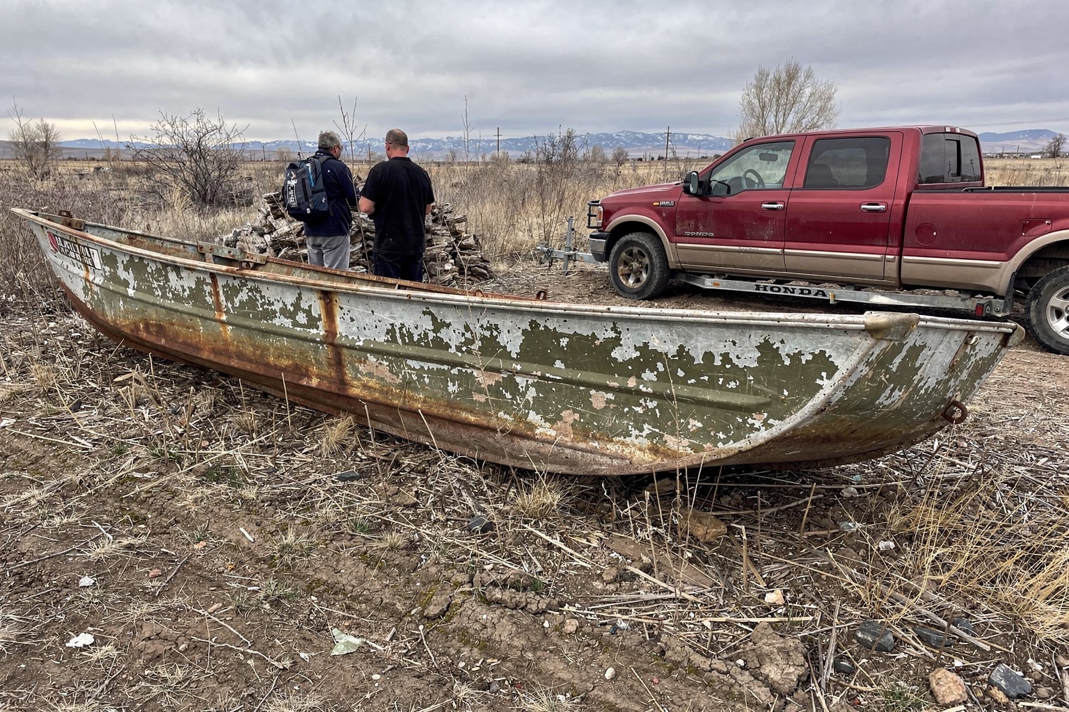 Abandoned junk boat in Colorado yard with salvage truck approaching for marine salvage removal