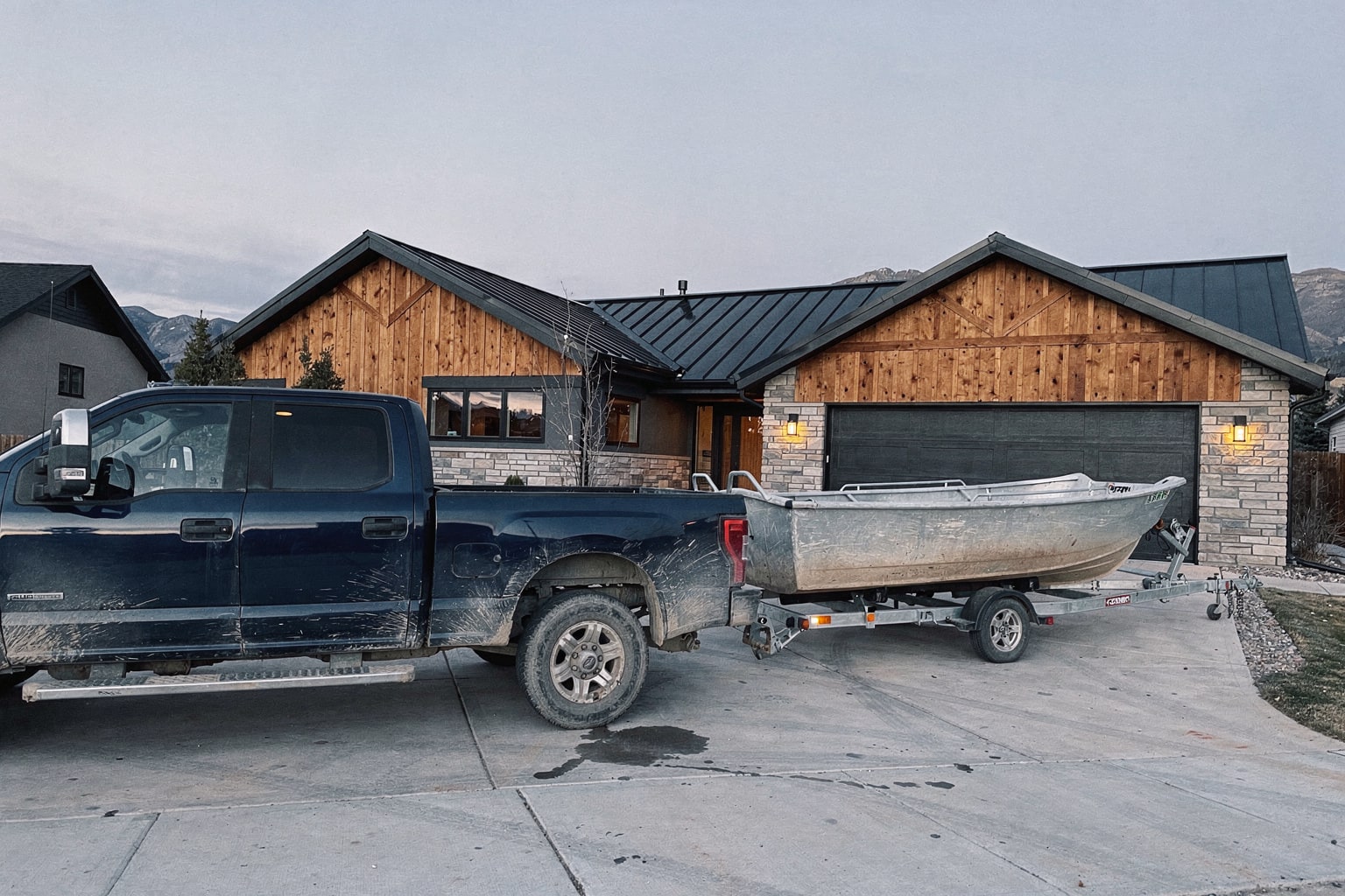 Junk boat removal Denver CO — weathered powerboat loaded on trailer behind pickup truck in residential driveway