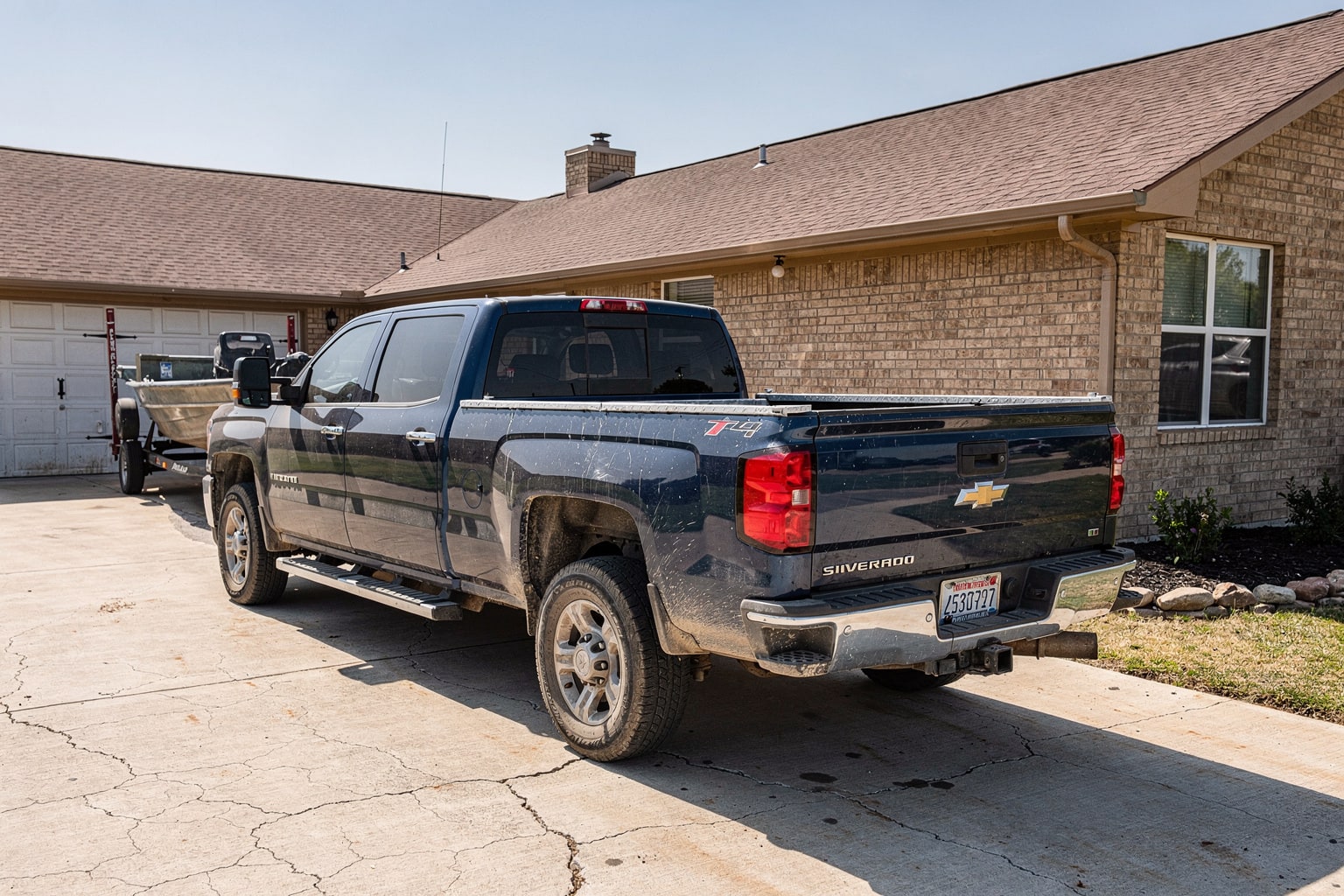Dark blue Chevy pickup truck with weathered aluminum fishing boat on trailer in Fort Worth driveway