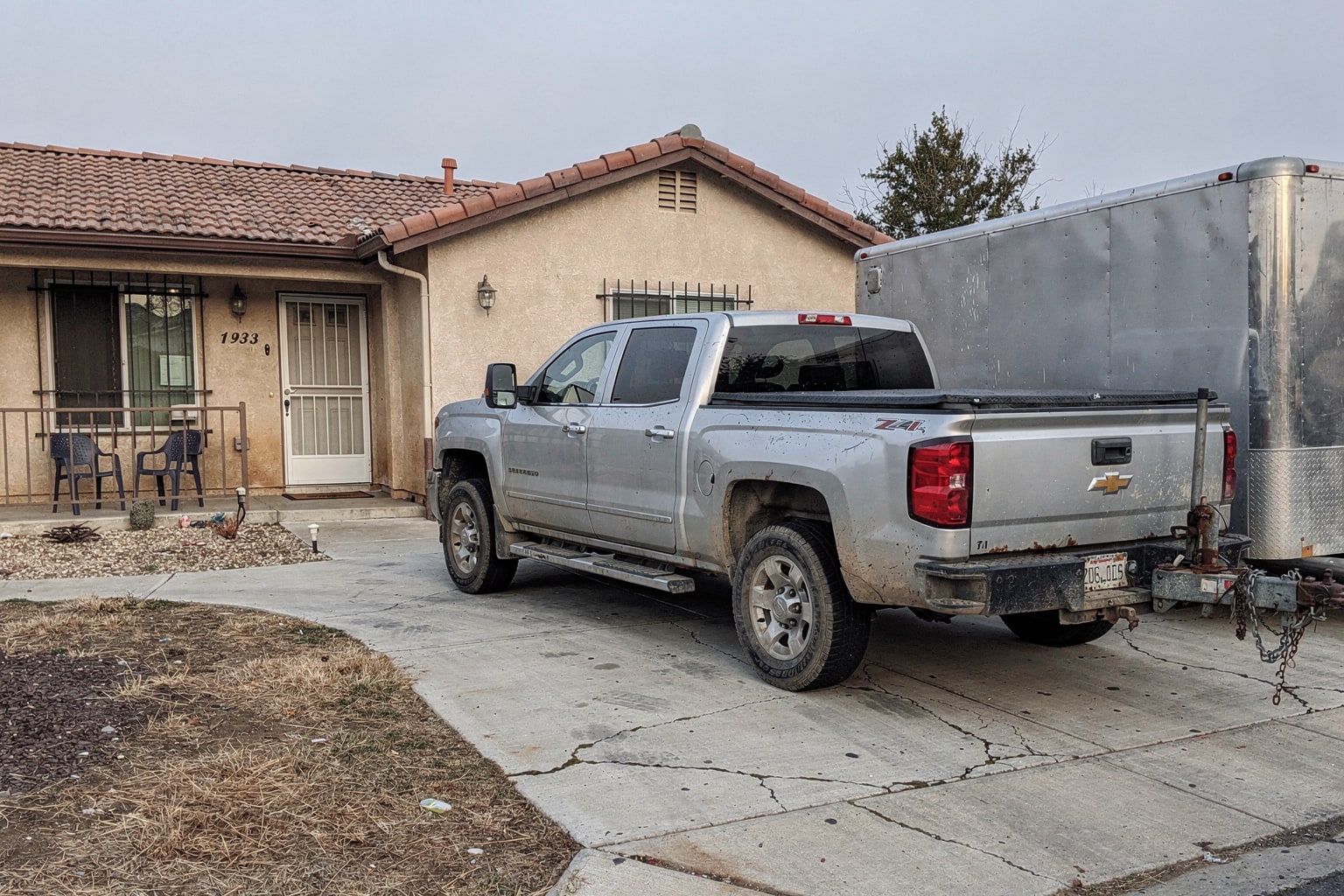 Junk boat removal Fresno California, weathered aluminum fishing boat loaded on trailer behind pickup truck in residential driveway