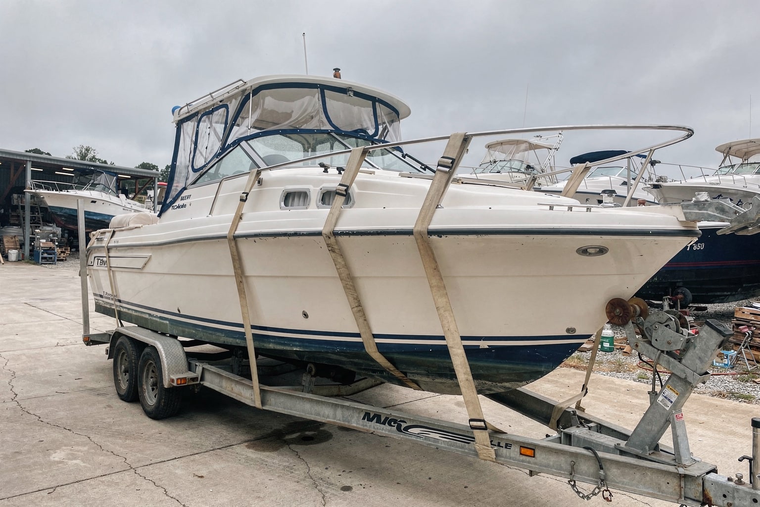 Professional boat removal Georgia boatyard showing cabin cruiser on hydraulic trailer with tow truck and marine salvage facility.