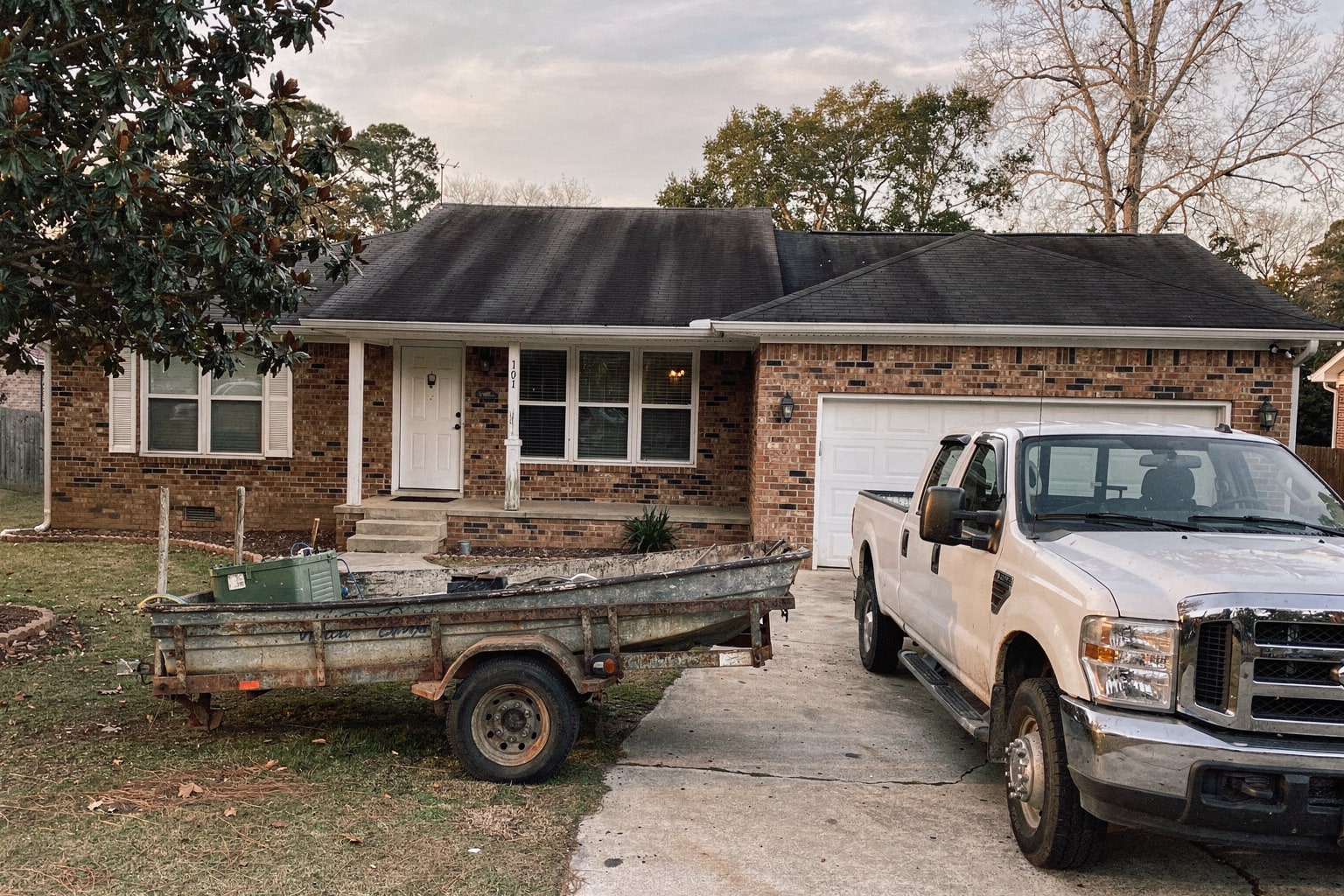 Junk boat removal service in Georgia showing weathered fishing boat loaded on trailer with pickup truck ready for salvage.