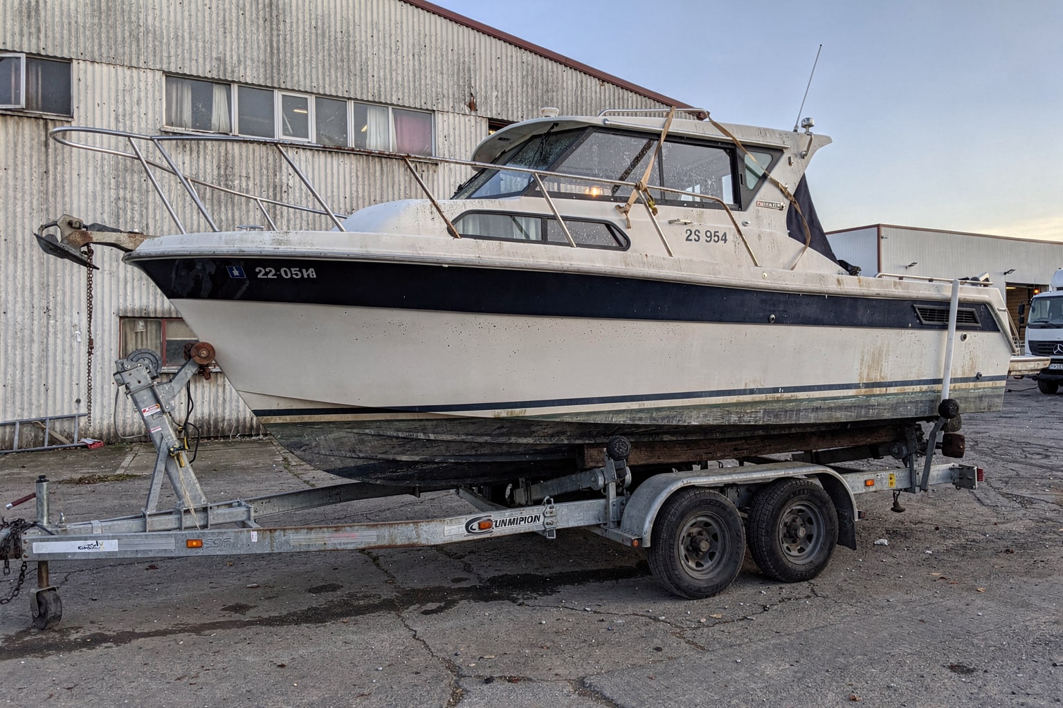 Commercial boat salvage operation Illinois warehouse, 22-foot cabin cruiser on hydraulic trailer for junk boat disposal