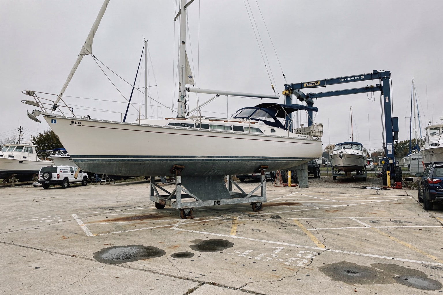 Marine salvage sailboat on cradle at Indiana boatyard with travel-lift and other vessels in background