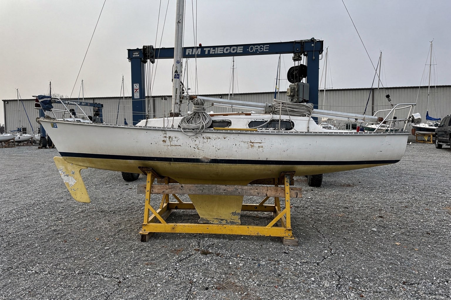22-foot sailboat on cradle at Iowa boatyard with travel-lift staged for removal and salvage
