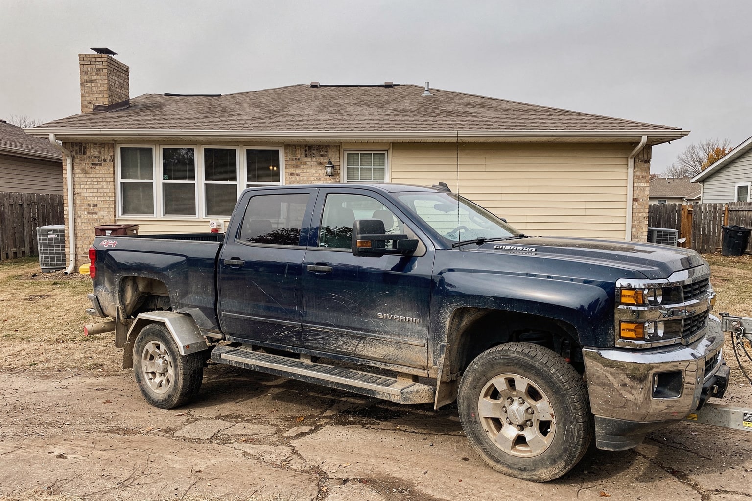 Junk boat removal Kansas City featuring weathered pontoon boat on pickup truck trailer in residential side yard