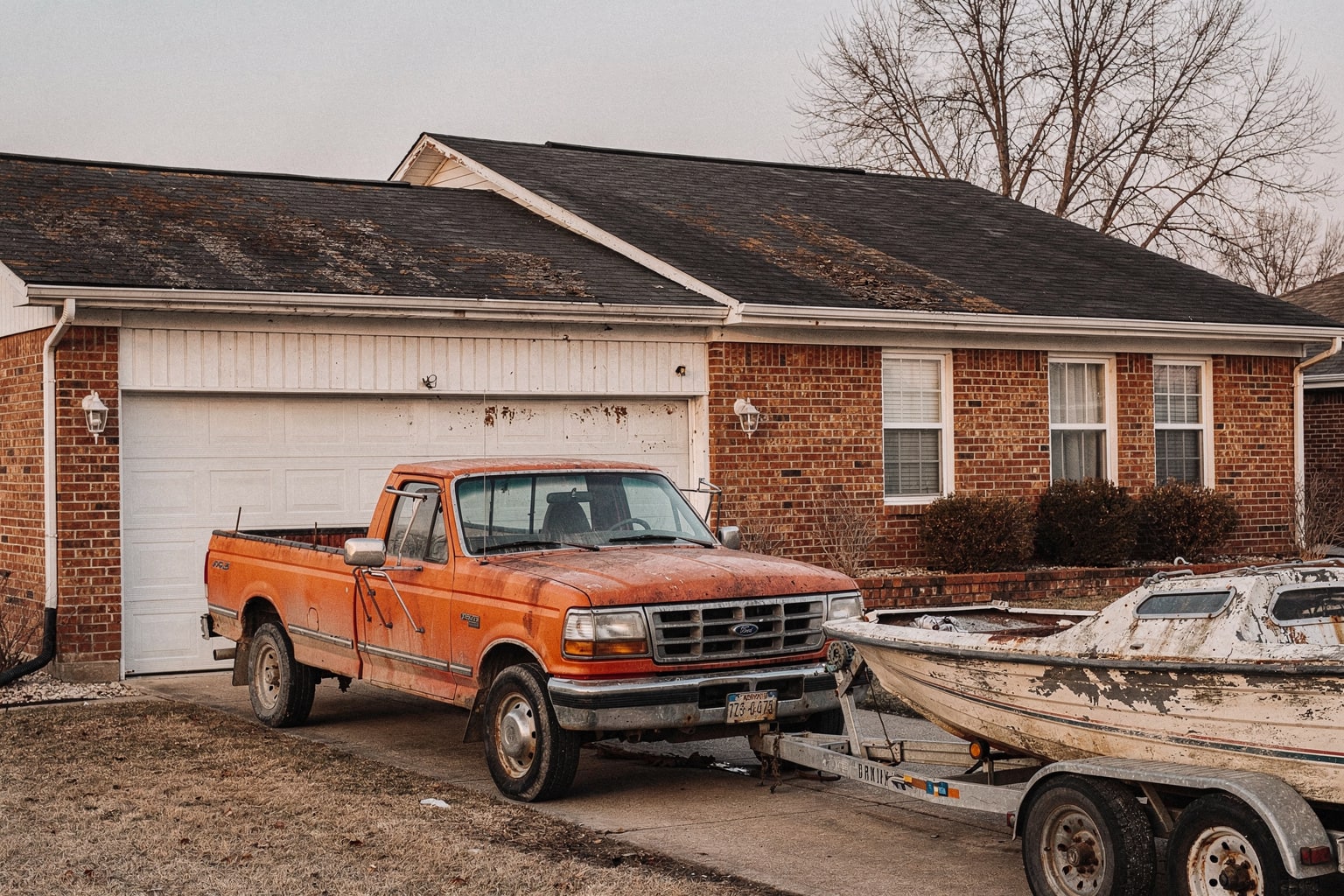 Junk sailboat removal in Kansas City showing unstepped sailboat on aged pickup truck trailer in residential driveway
