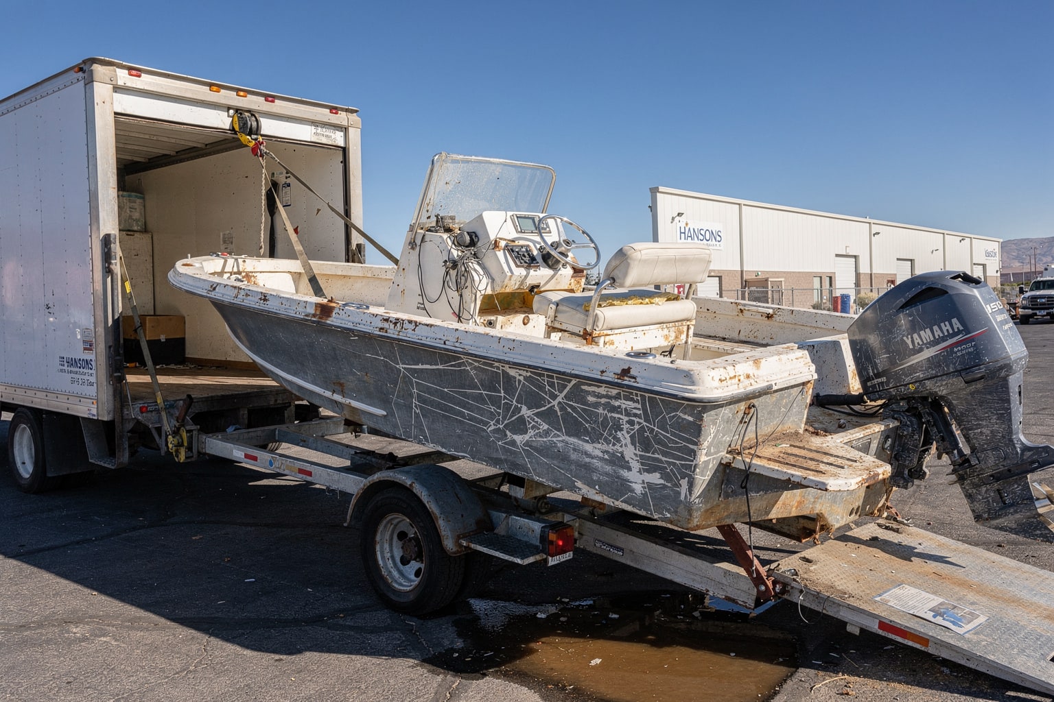 Commercial boat removal in Las Vegas showing junk powerboat loaded onto disposal truck at warehouse