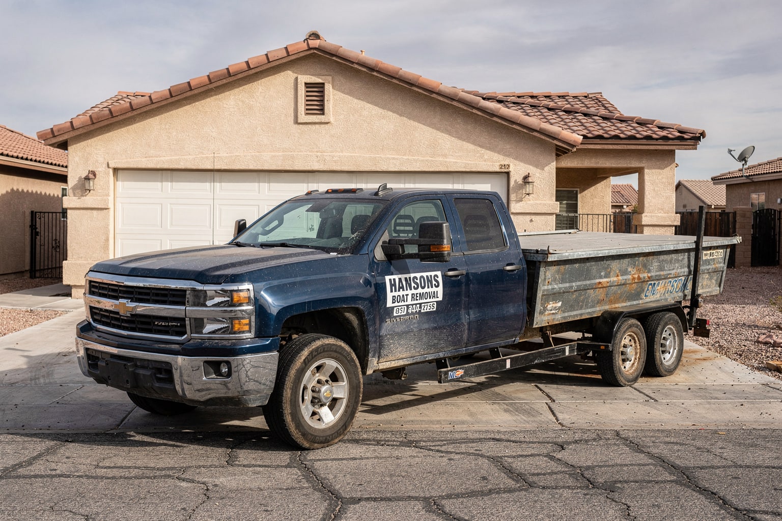 Junk boat removal in Las Vegas driveway with deteriorated fishing boat loaded on pickup truck trailer