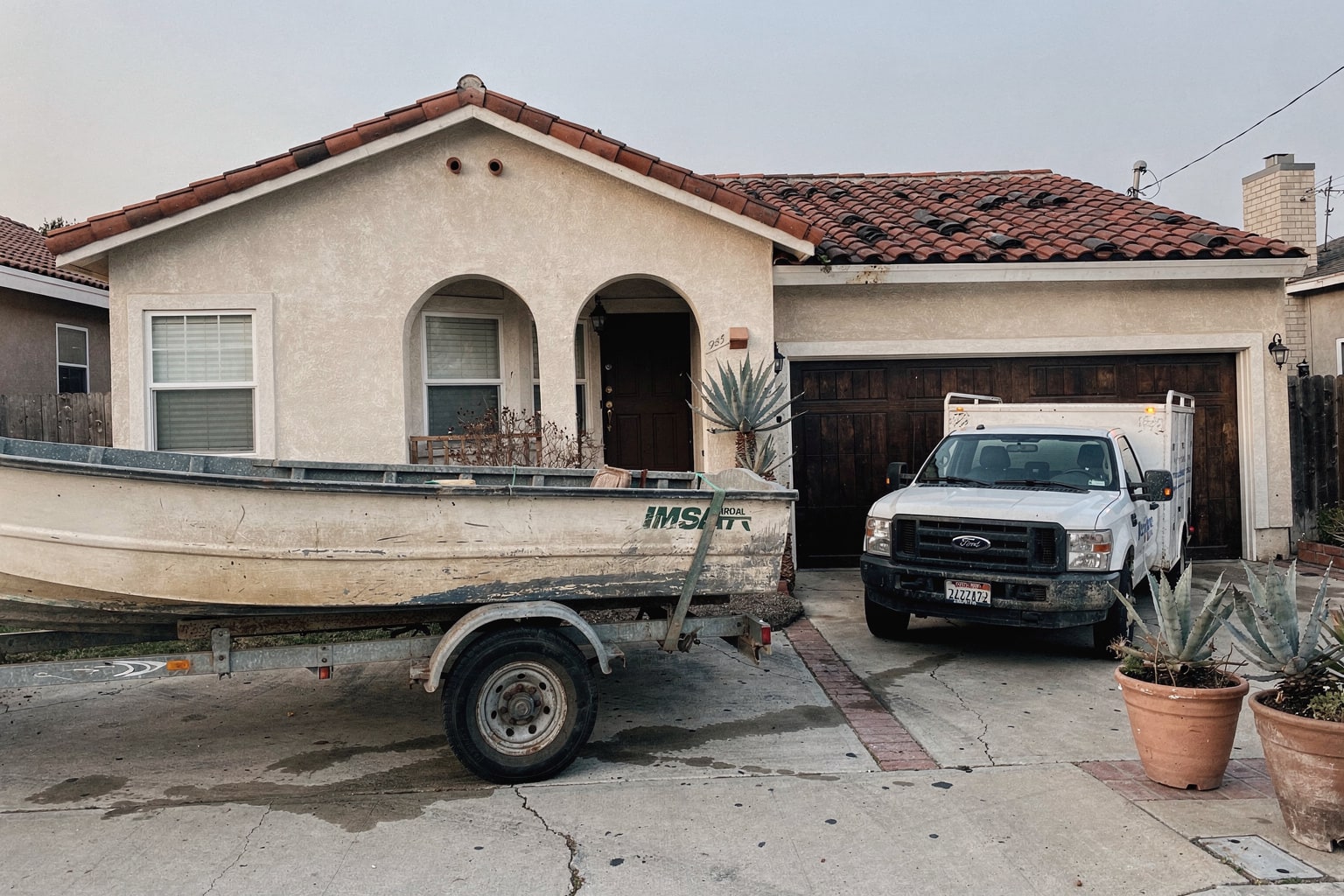 Junk boat removal in Long Beach showing old fiberglass powerboat loaded on trailer behind pickup truck