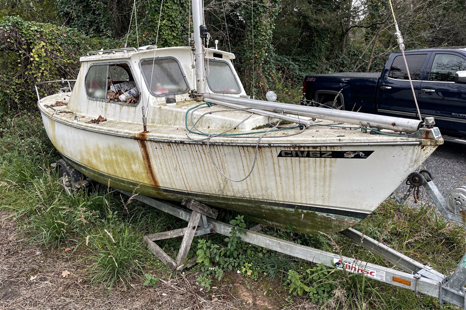 Abandoned boat removal Maryland: salvage operation for derelict sailboat in overgrown riverside property