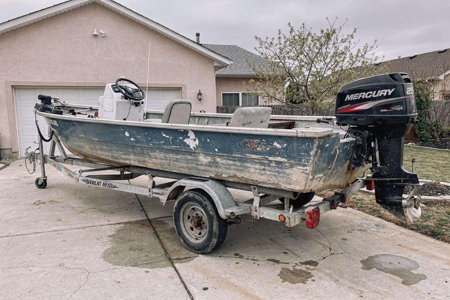 Maryland boat removal service showcasing weathered aluminum fishing boat loaded on trailer behind pickup truck in residential driveway