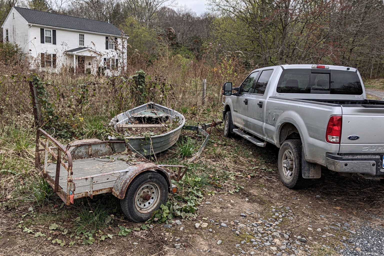 Abandoned aluminum jon boat in overgrown Massachusetts lot surrounded by weeds and kudzu vines ready for removal