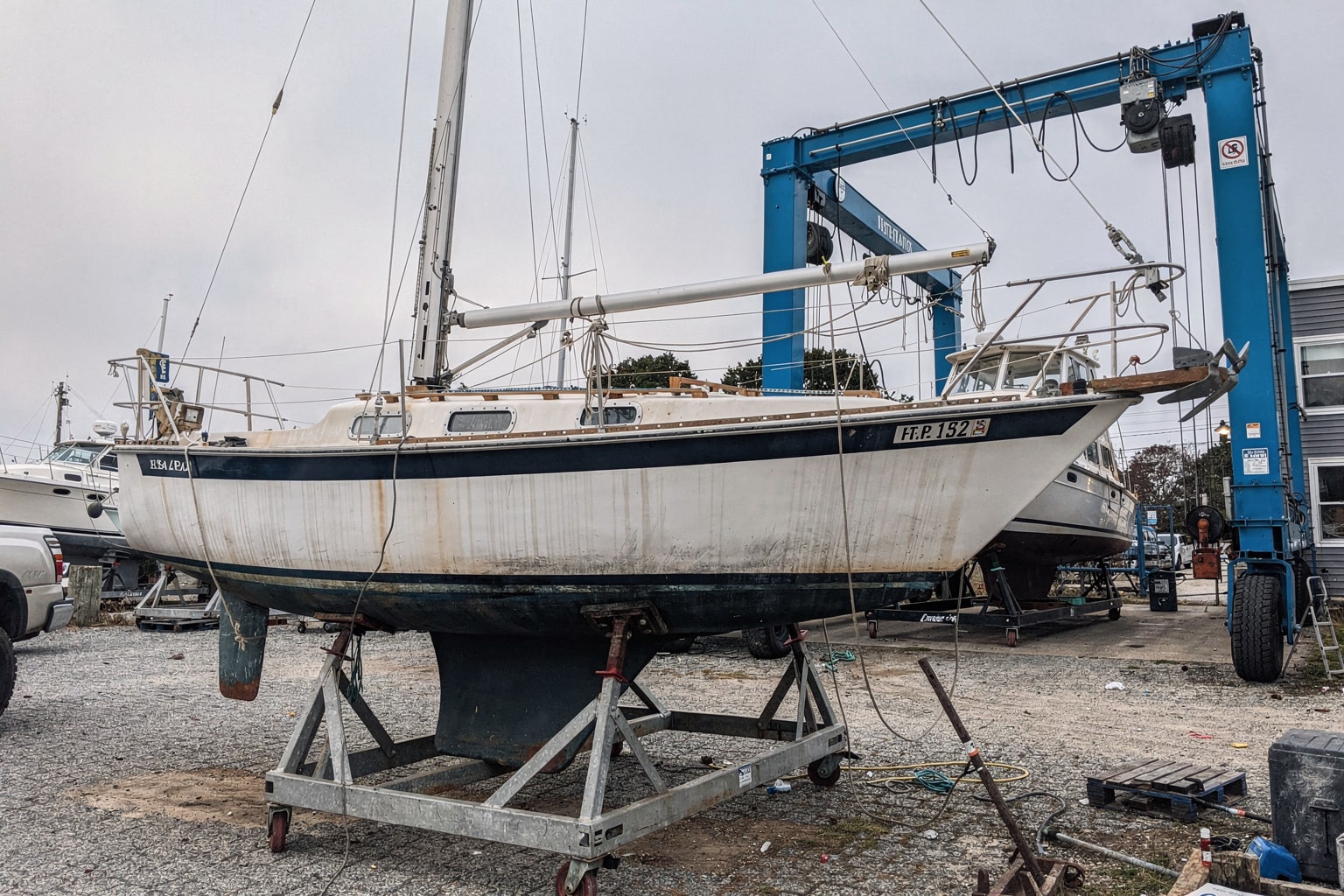 32-foot sailboat on steel cradle in Massachusetts boatyard dry storage surrounded by other vessels and travel-lift
