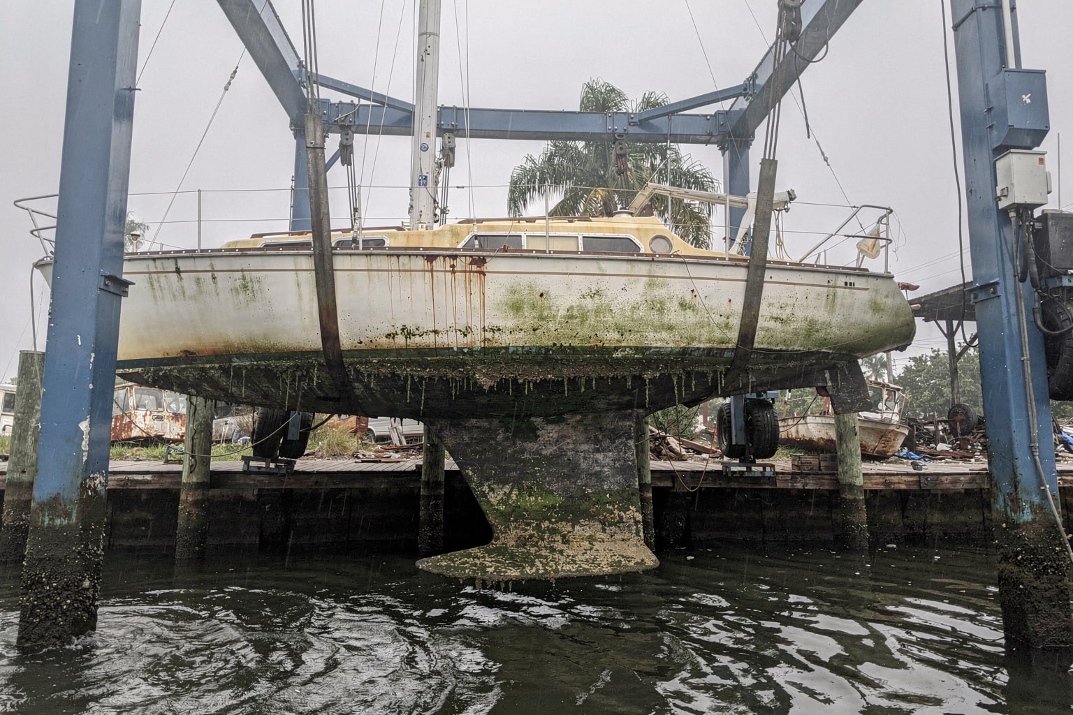 Junk boat removal Miami marina travel-lift suspended deteriorated sailboat disposal service
