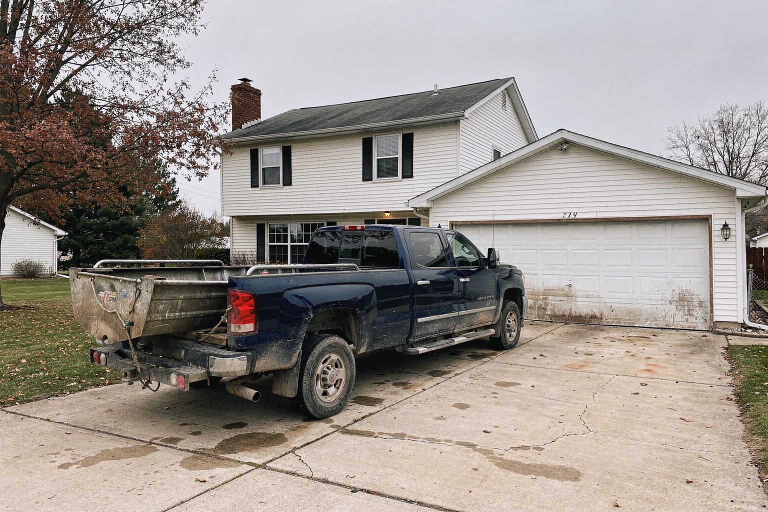 Weathered aluminum fishing boat loaded on trailer behind dark blue pickup truck in Michigan driveway during junk boat removal service