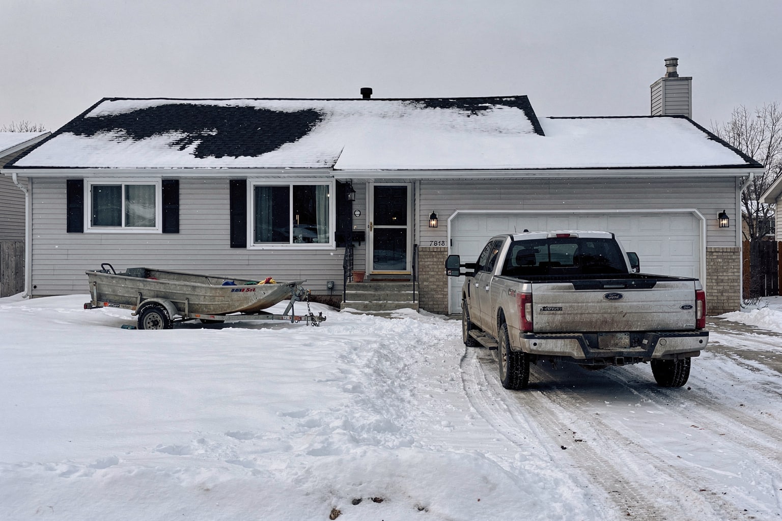 Junk boat removal Minneapolis winter driveway pickup truck and trailer loaded with damaged aluminum fishing boat