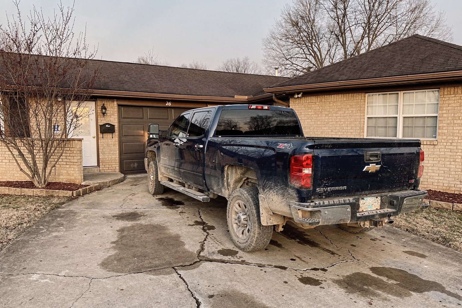 weathered center console powerboat on single-axle trailer behind pickup truck, Missouri residential driveway removal