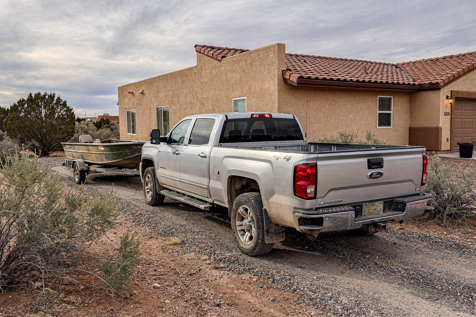 Aluminum fishing boat on trailer behind pickup truck in New Mexico driveway during boat removal service
