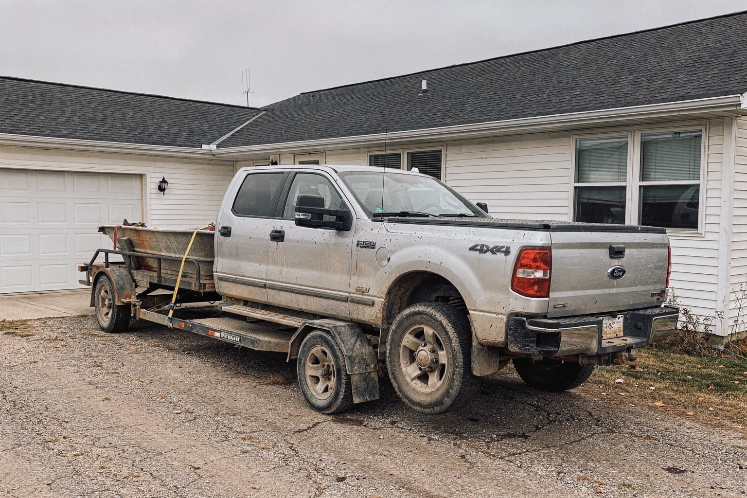 Junk boat removal North Dakota pickup truck with weathered aluminum fishing boat on trailer in residential driveway