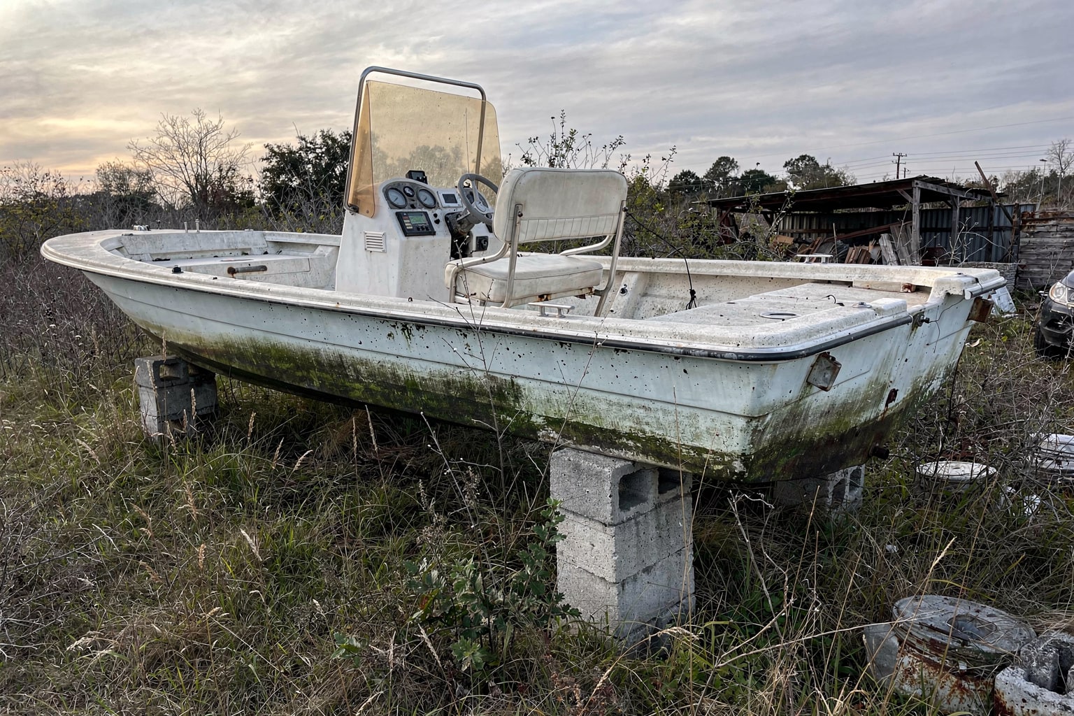 Junk boat removal Oakland — abandoned fiberglass boat disposal from overgrown California backyard