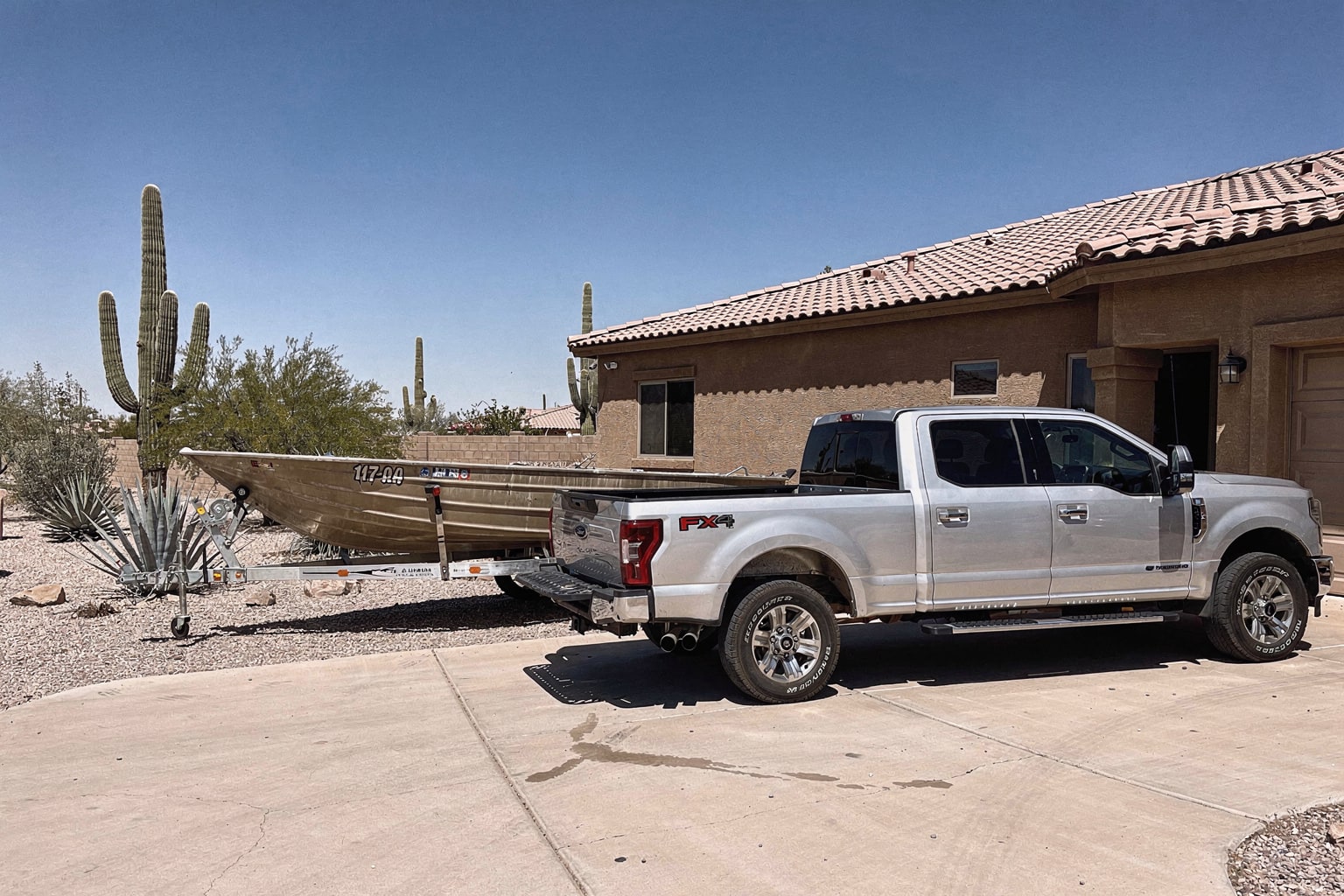 Silver pickup truck and trailer with aluminum fishing boat ready for removal in Phoenix residential driveway