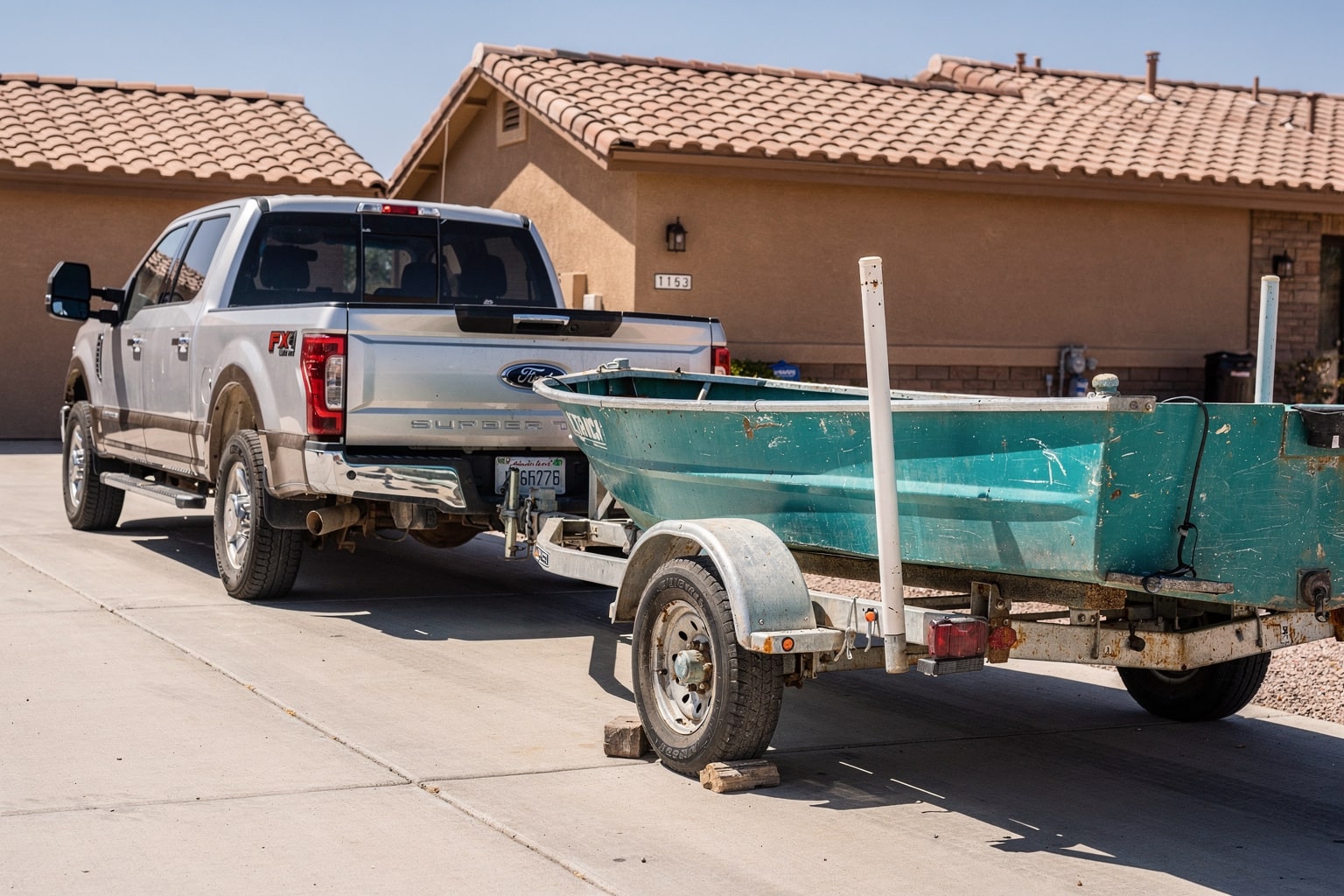 Weathered aluminum fishing boat loaded on trailer ready for junk boat removal in Phoenix Arizona residential driveway
