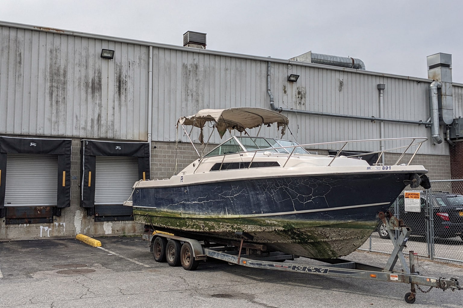 Large junk boat removal from Queens NY commercial warehouse, boat disposal on industrial tandem trailer