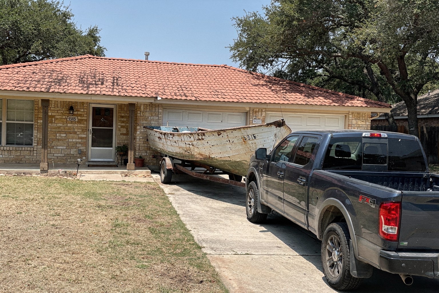 Junk boat removal San Antonio — weathered boat on trailer with pickup truck ready for disposal