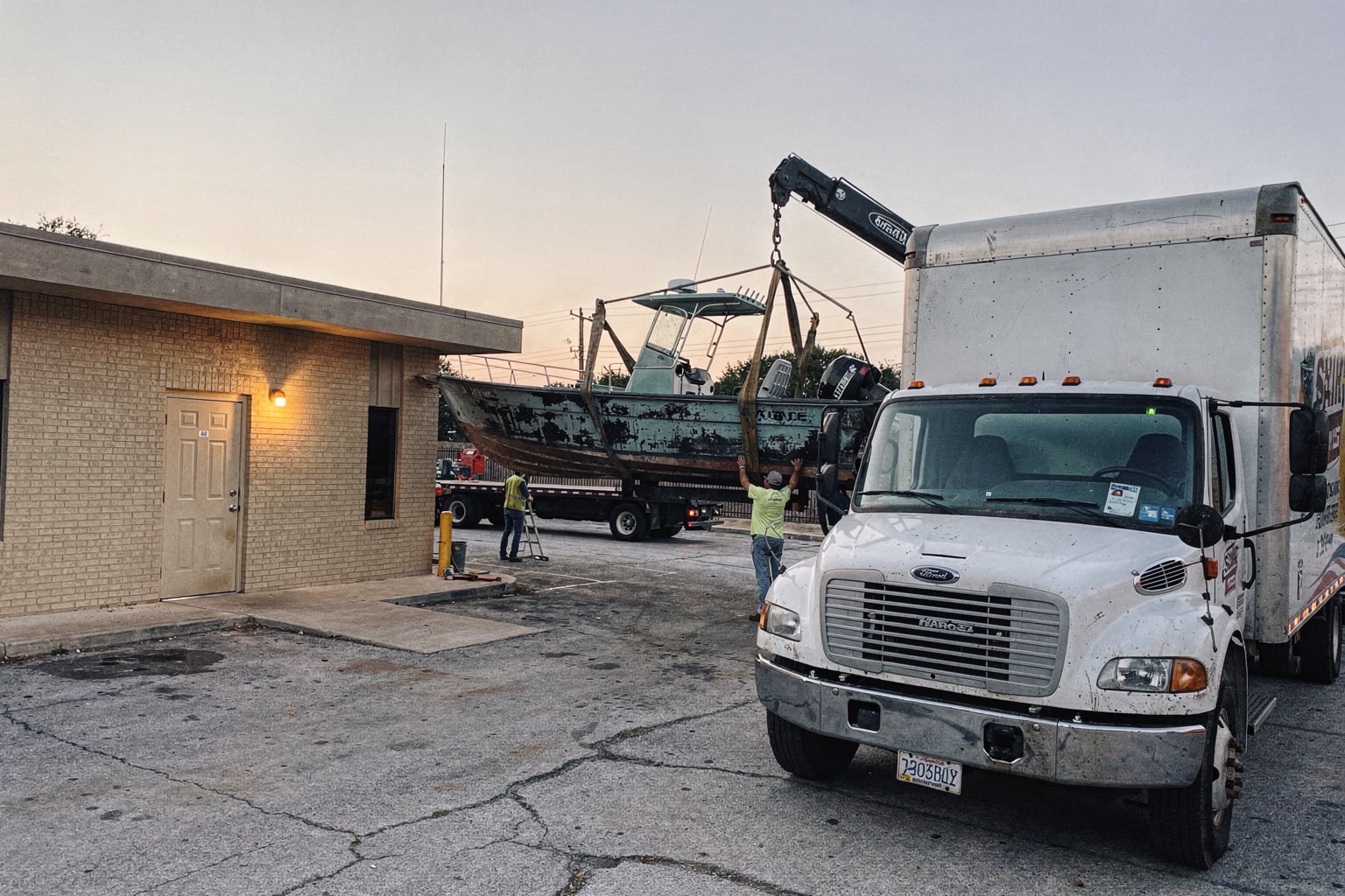 Professional boat disposal San Antonio — large junk boat removal crew securing boat on commercial trailer