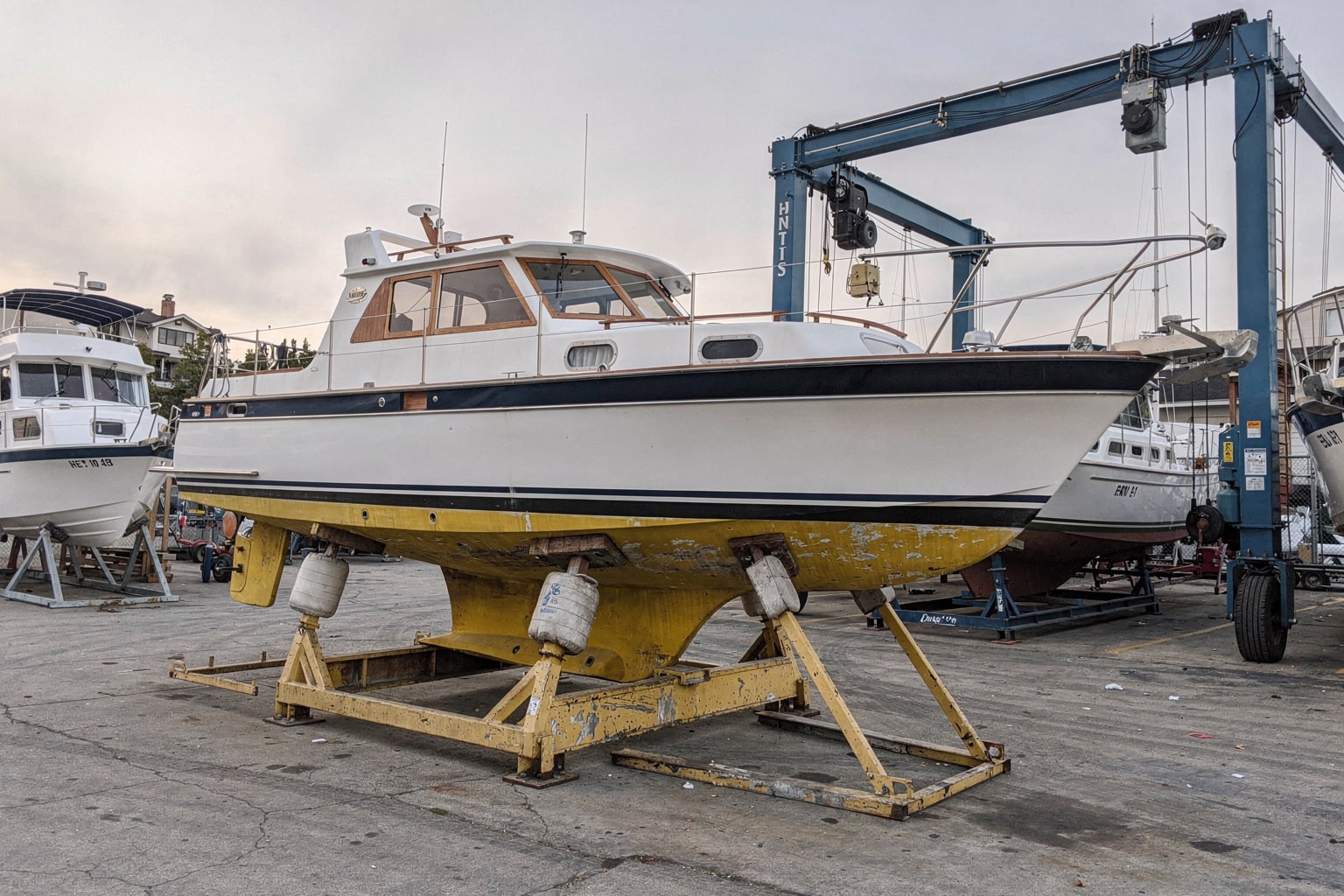 Junk boat removal San Diego boatyard — large sailboat on steel cradle with mast removed, ready for disposal