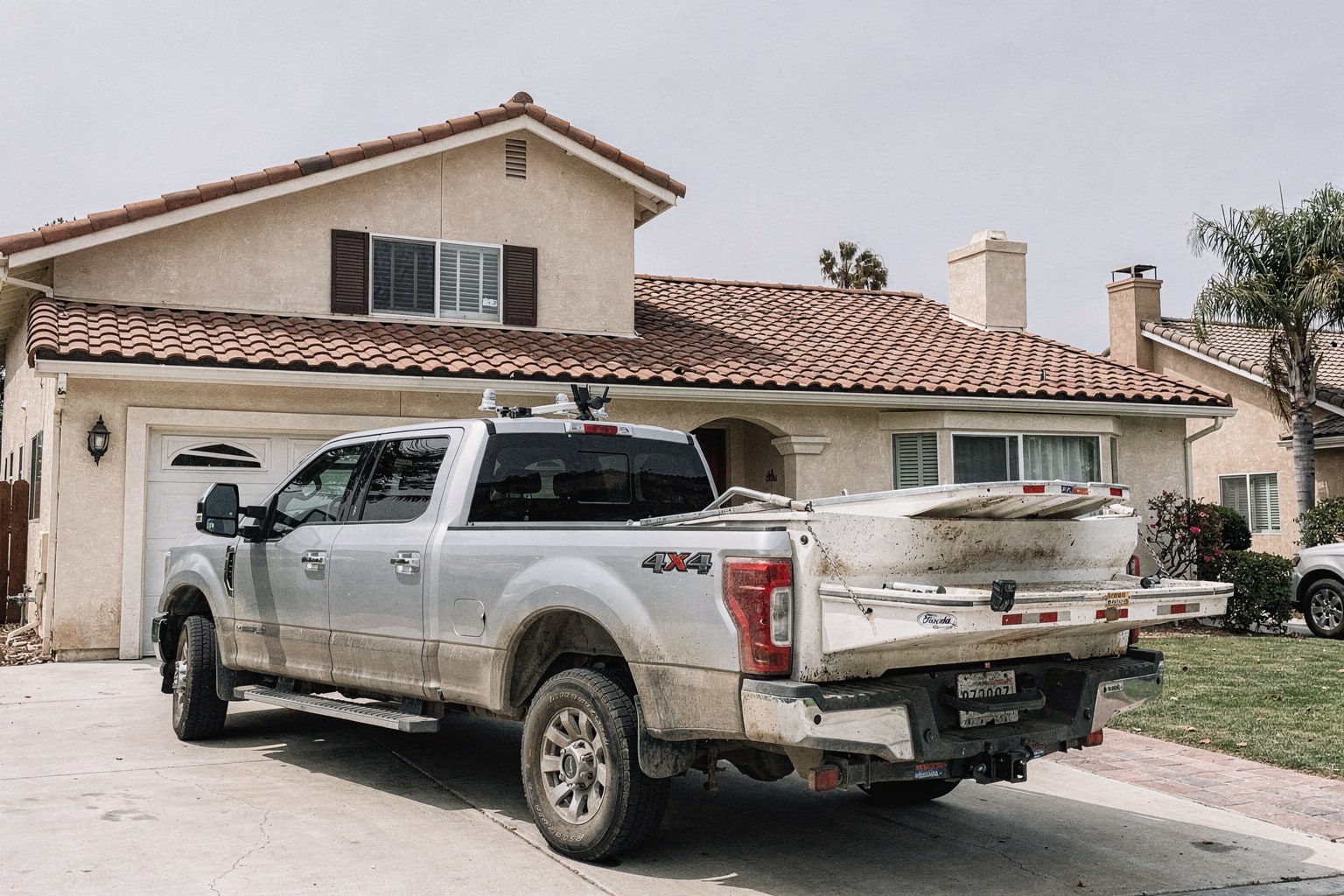 Junk boat removal San Diego — weathered powerboat loaded on trailer behind pickup truck in residential driveway