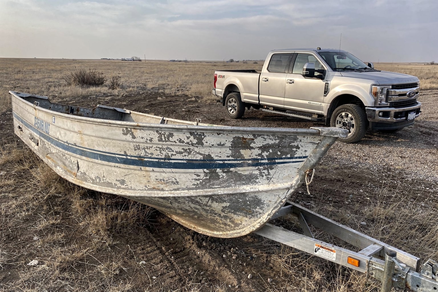Weathered aluminum fishing boat on South Dakota property ready for junk boat removal and salvage