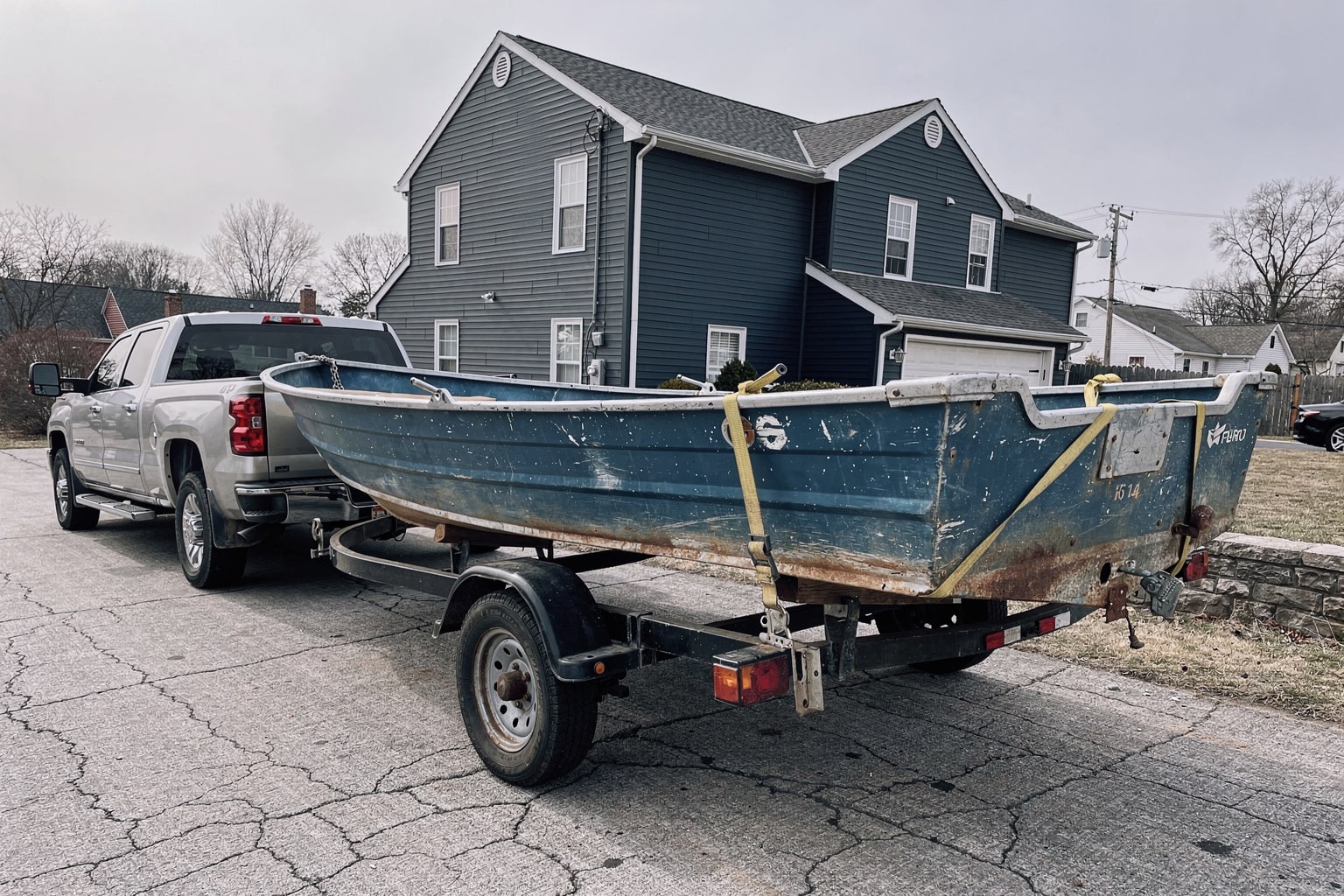 Staten Island boat removal service showing junk boat loaded on trailer behind pickup truck in residential driveway