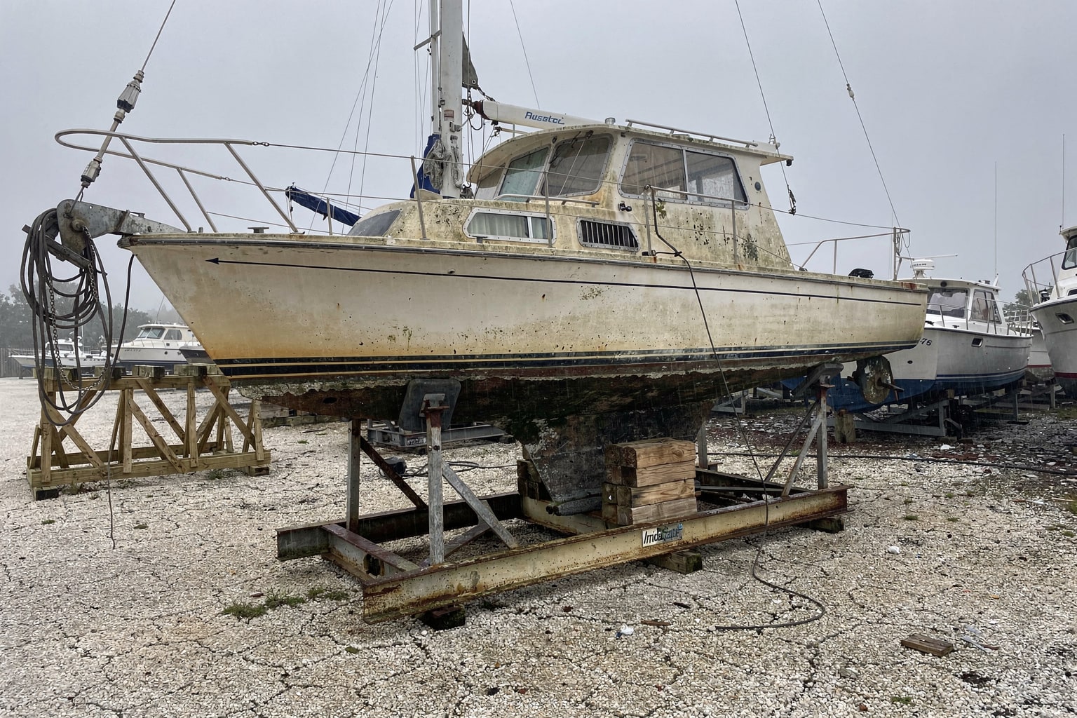 Junk sailboat removal Tampa boatyard with 32-foot vessel on cradle and travel-lift ready for disposal