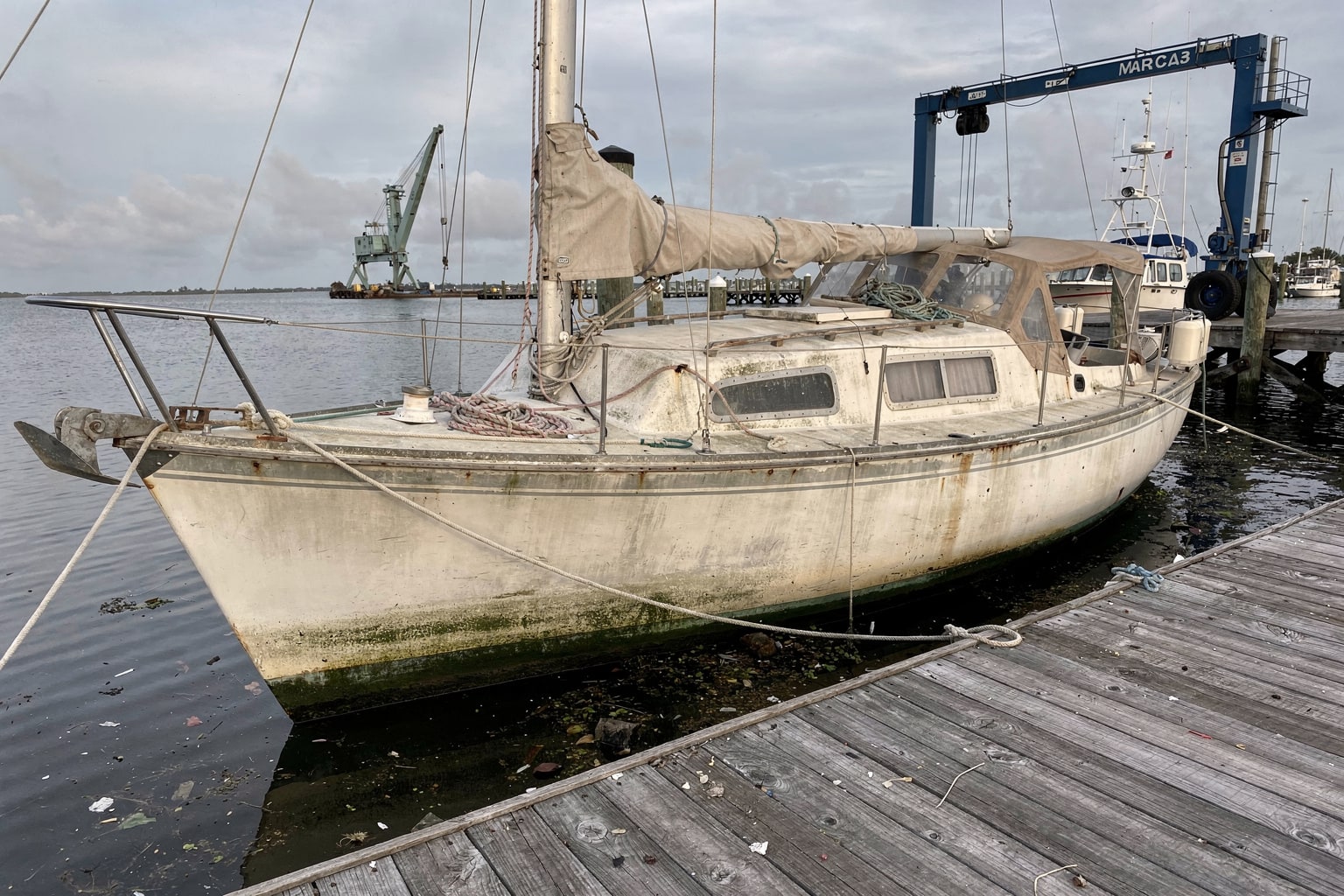 Junk boat removal Tampa marina with weathered sailboat moored for disposal haul-out