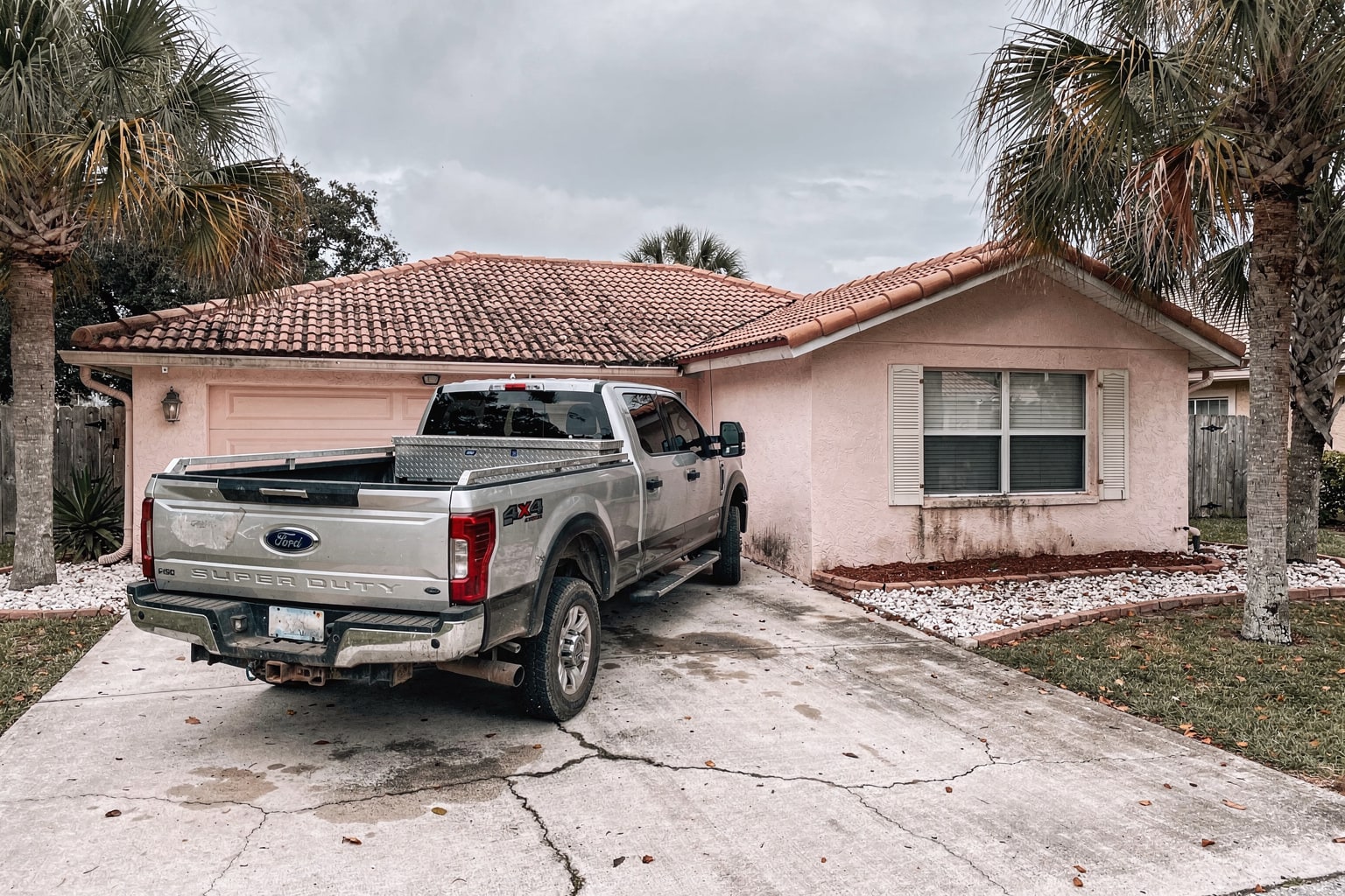 Junk boat removal Tampa driveway with pickup truck and weathered fiberglass fishing boat on trailer ready for disposal