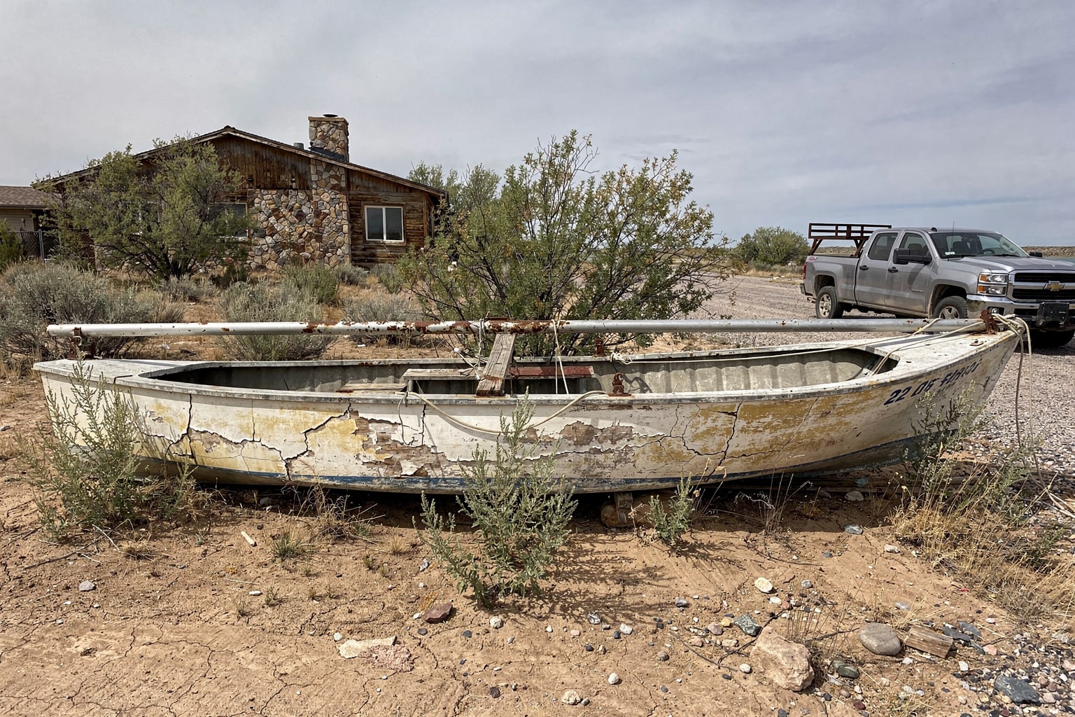 Abandoned deteriorated sailboat salvage in rural Utah with overgrown property