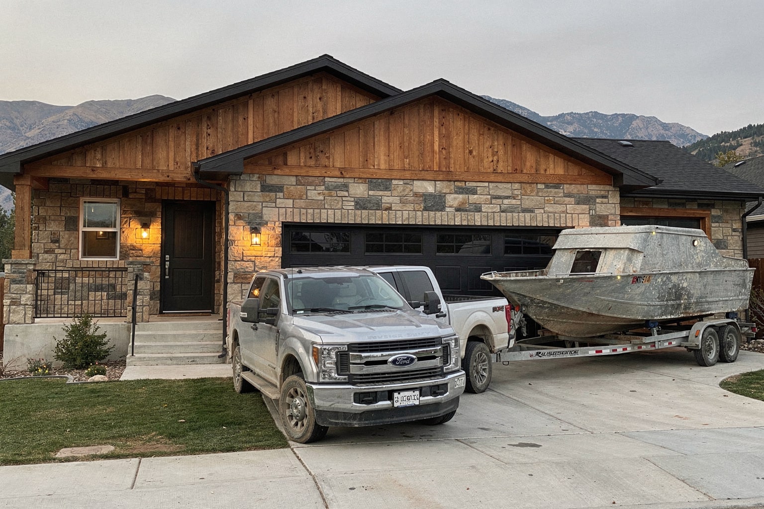 Weathered boat removal on Utah driveway with pickup truck and trailer, mountain backdrop