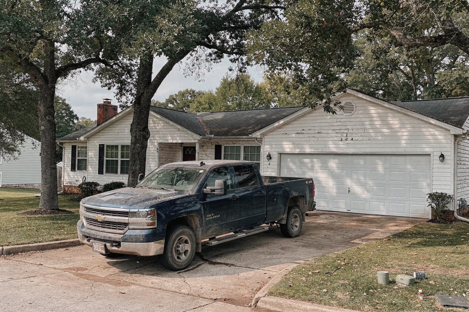 Dark blue pickup truck with weathered powerboat loaded lengthwise on trailer in Virginia residential driveway