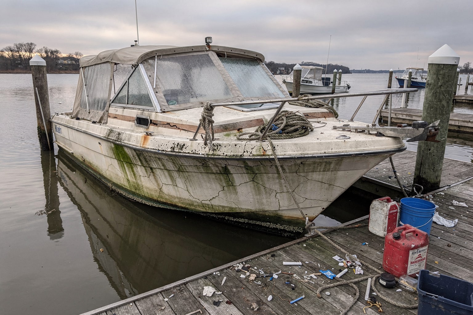 Neglected 22-foot cabin cruiser moored at Washington DC marina dock, junk boat removal